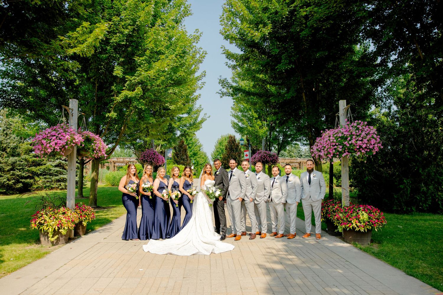 Wedding party in navy and gray poses outdoors with colorful floral arrangements.