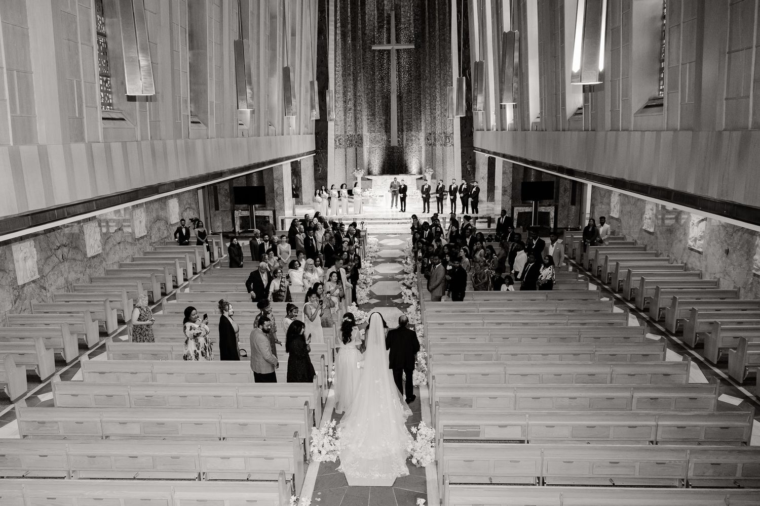 Black and white photograph of church ceremony with guests seated in wooden pews.