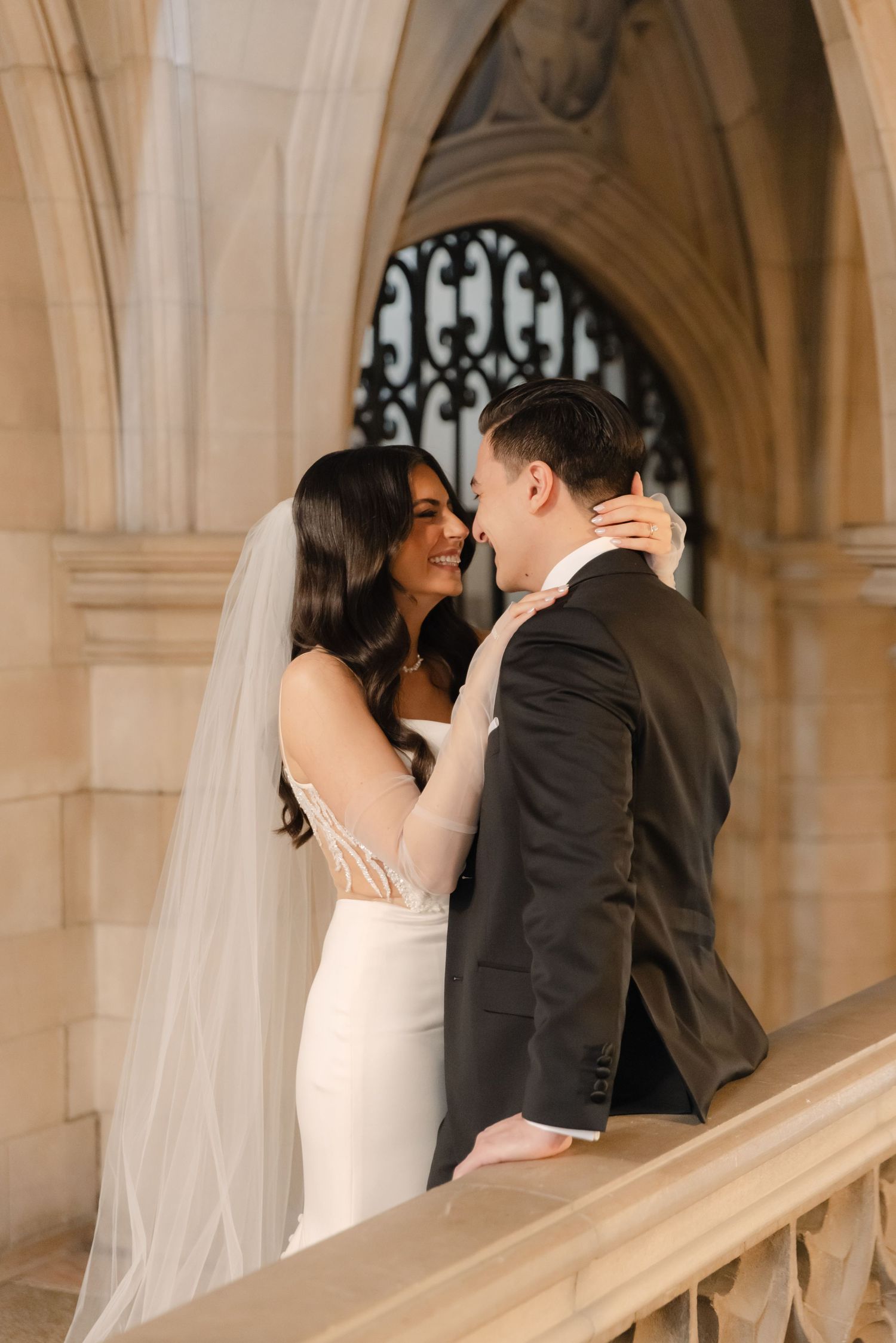 Intimate wedding moment captured on ornate marble staircase with vaulted ceiling.