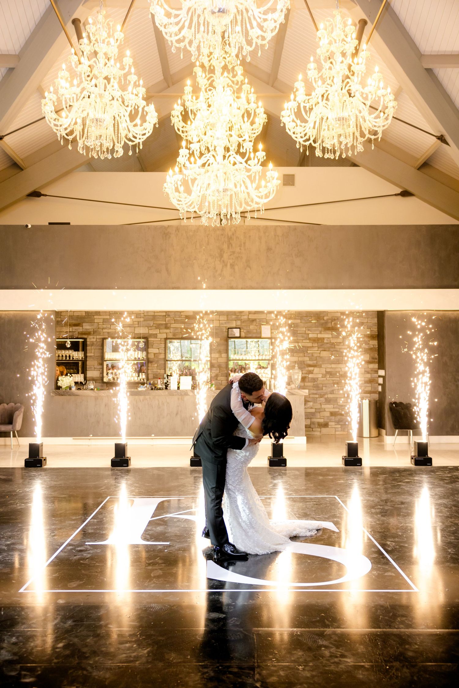 Sepia-toned wedding photo of couple's romantic dip on illuminated dance floor.