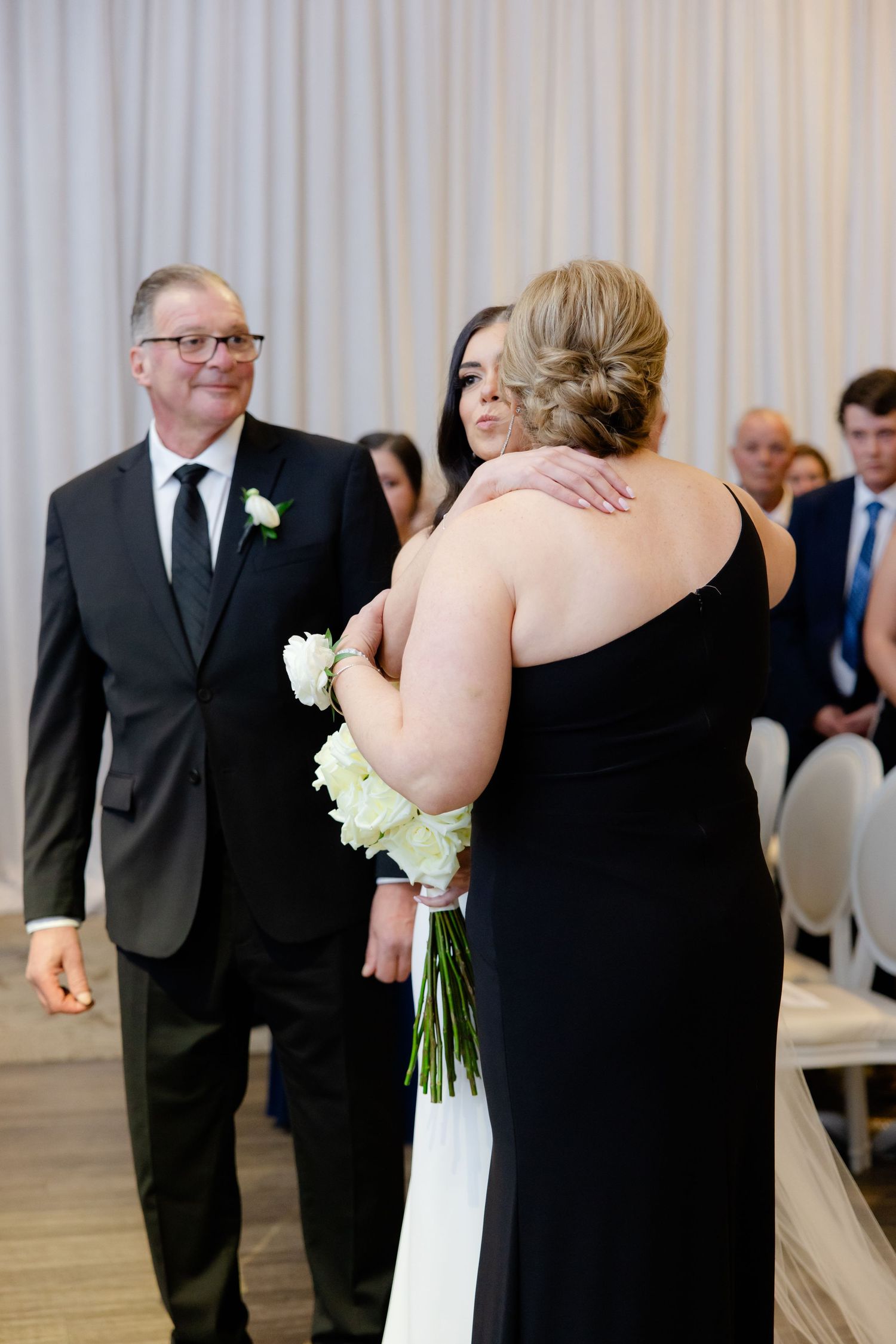 Intimate moment shared between wedding party members during the ceremony processional.