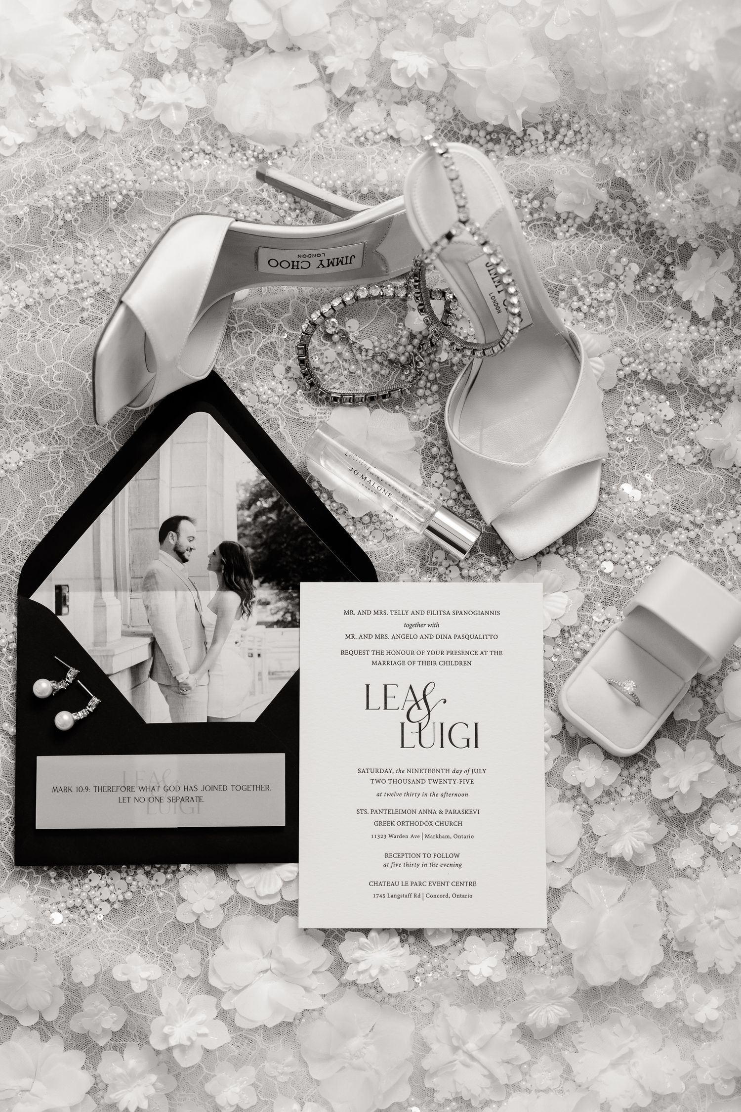Elegant black and white wedding invitation suite with ribbon details displayed on a textured marble background.