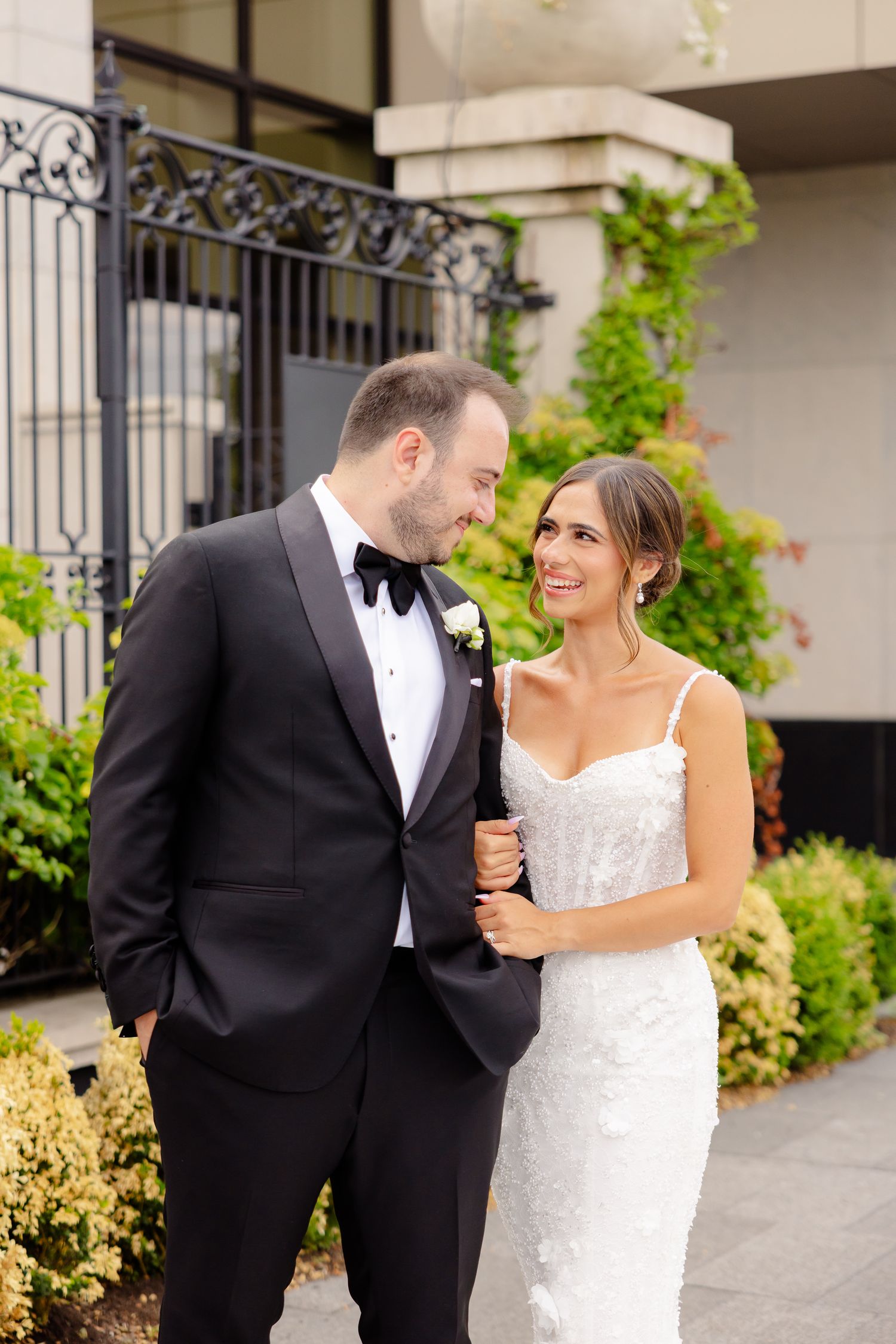 Wedding couple shares romantic and playful moments together in a garden setting while wearing formal attire.