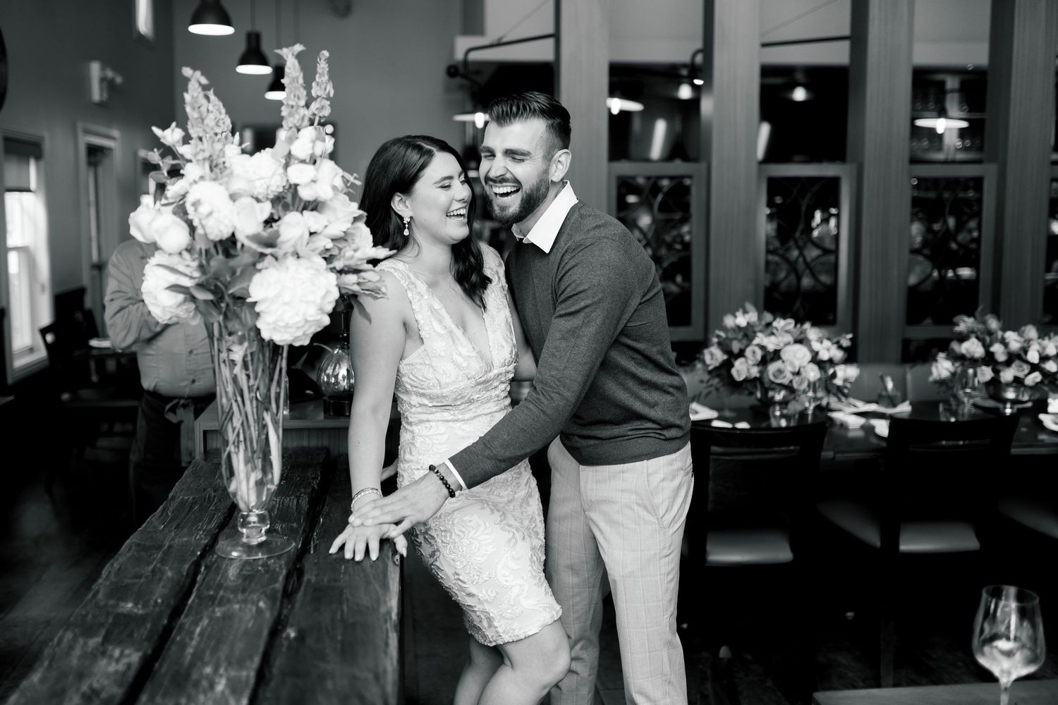 A joyful intimate moment between a couple near elegant floral arrangements in a modern indoor setting.