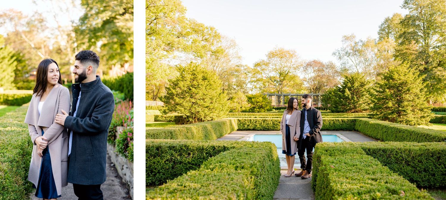 A couple enjoys a romantic stroll through a manicured garden with lush greenery.