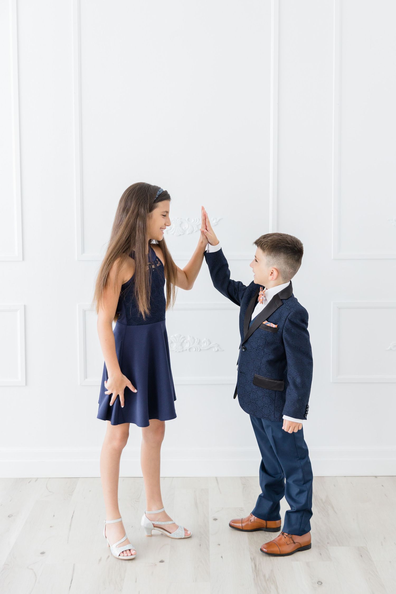 Two people give each other a high five while wearing formal navy and blue outfits.