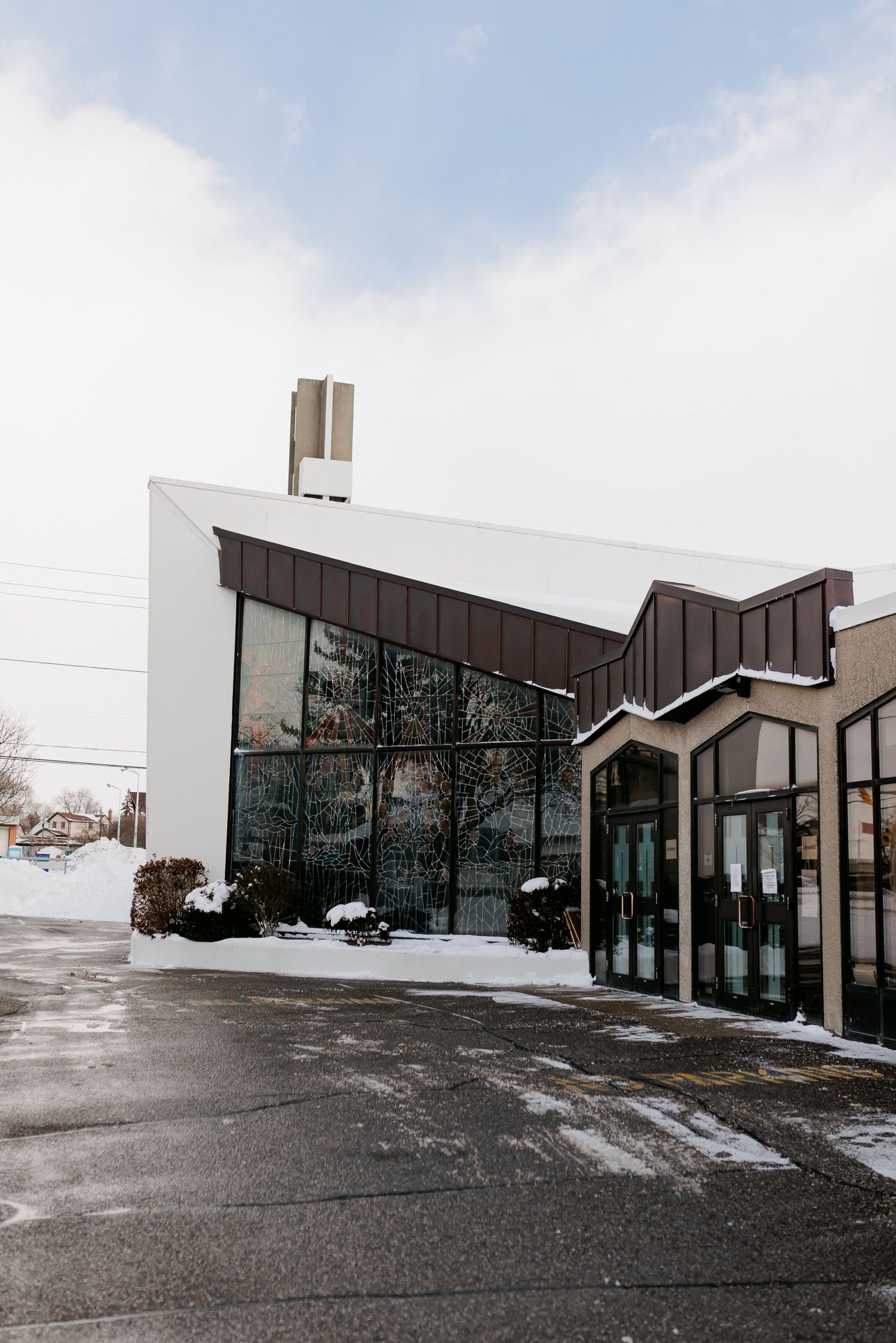 Modern church exterior with angled roof and glass walls covered in snow.