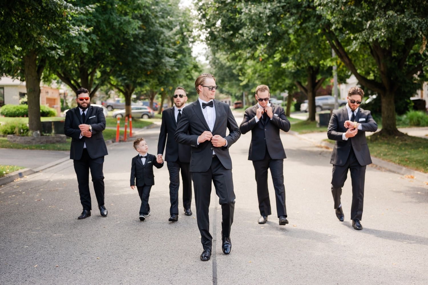 Groomsmen walking casually down sidewalk before wedding ceremony.