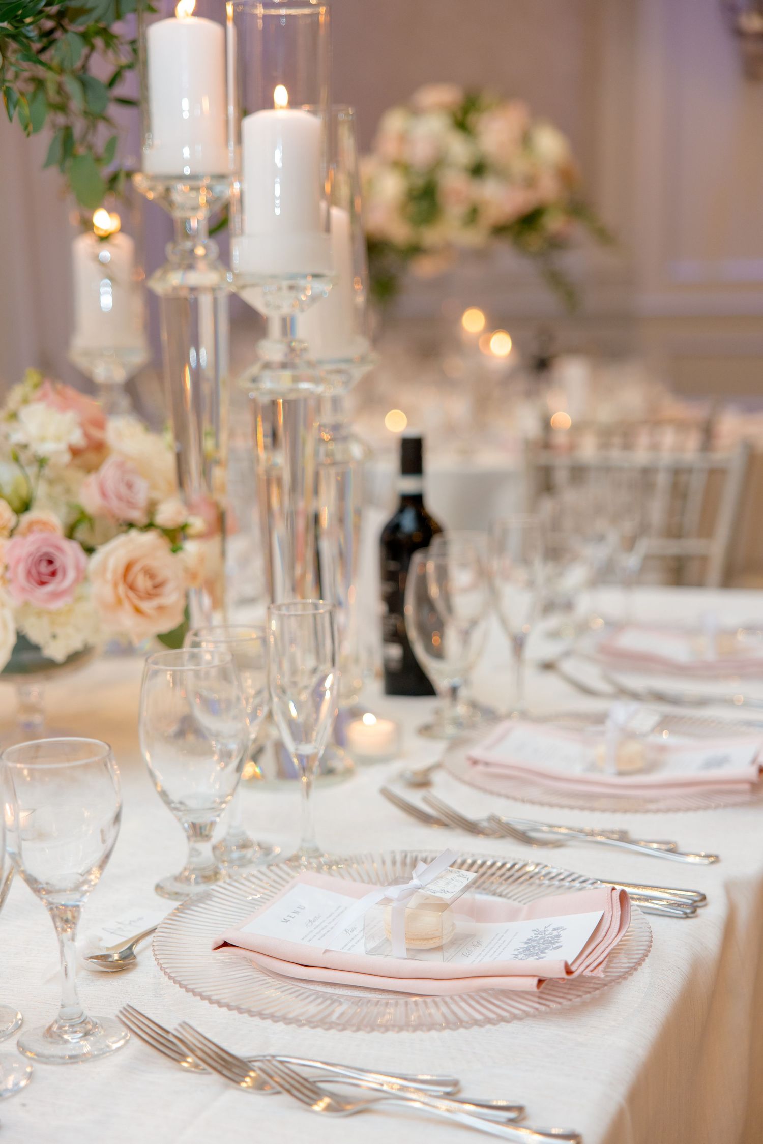 Wedding table setting with crystal candlesticks, pink napkins and white floral arrangements.