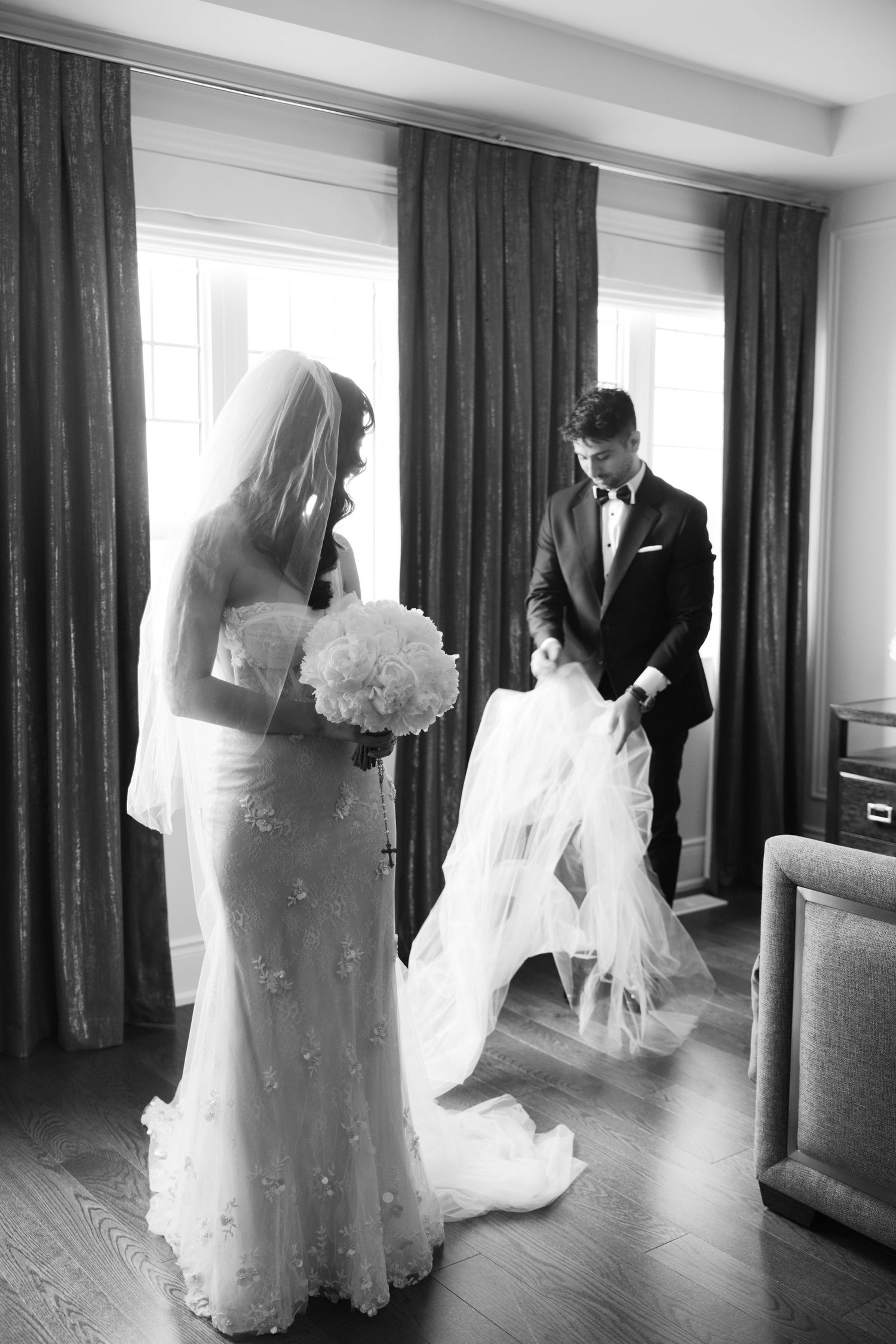 An intimate black and white moment with a bride in her gown holding a white bouquet.