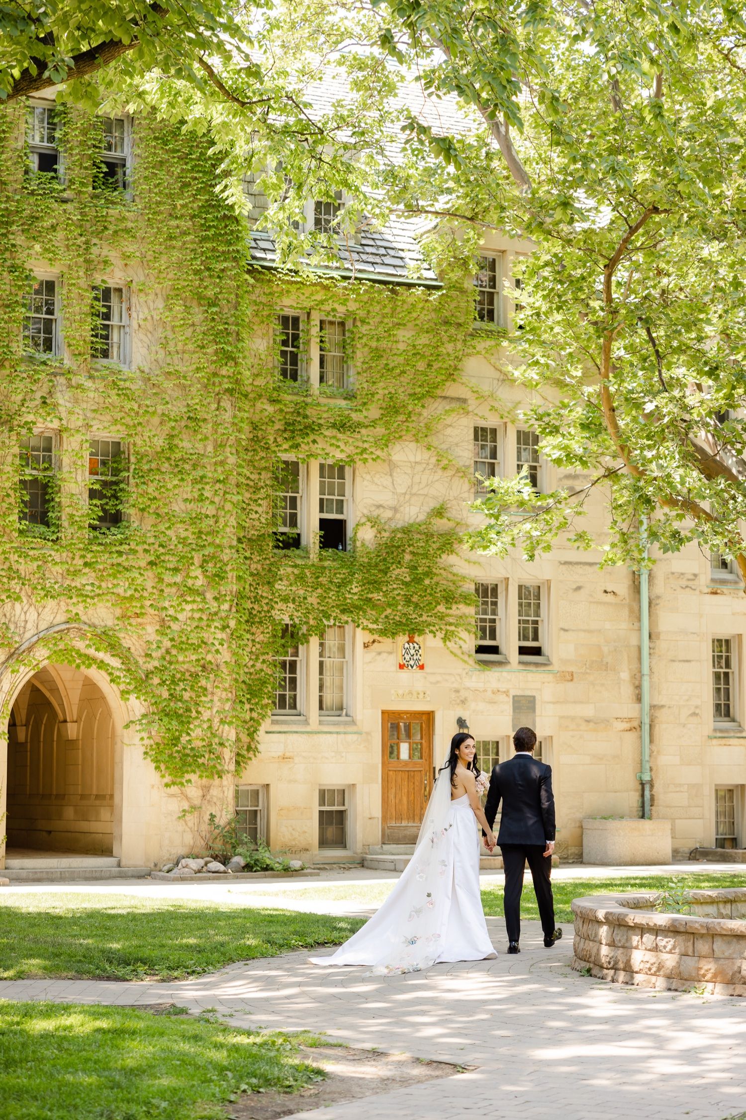 Couple stands in front of historic ivy-covered building with arched doorway.