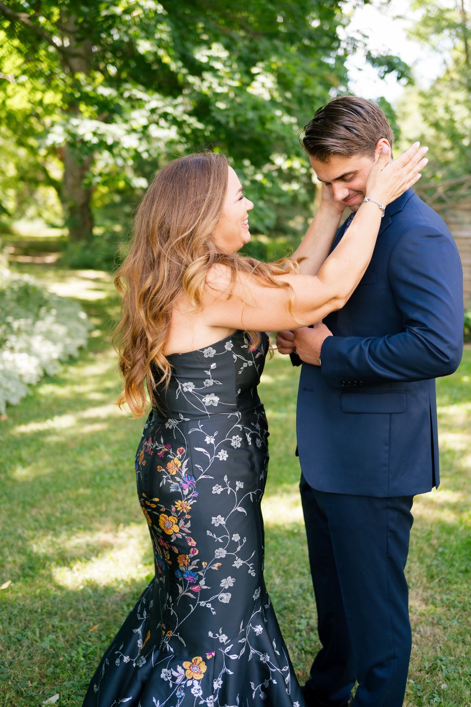 Intimate garden moment between couple in formal evening wear and navy suit.
