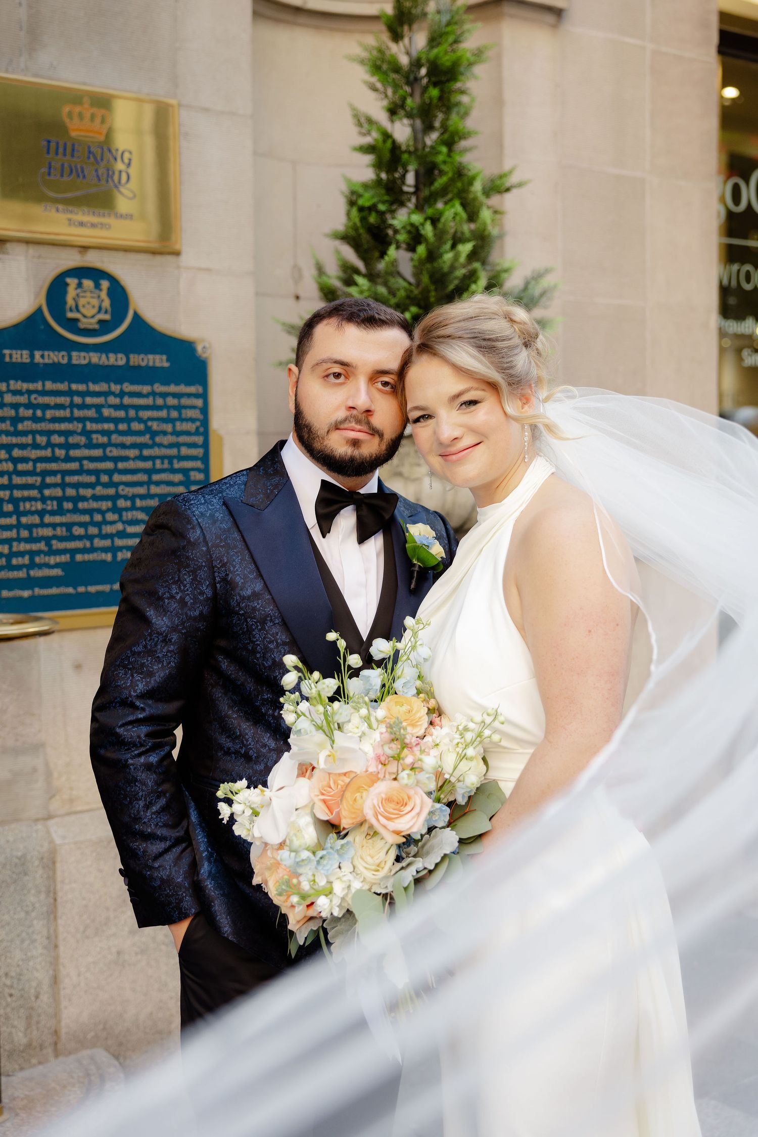 Elegant wedding photos capturing intimate moments between newlyweds against a stone building backdrop.