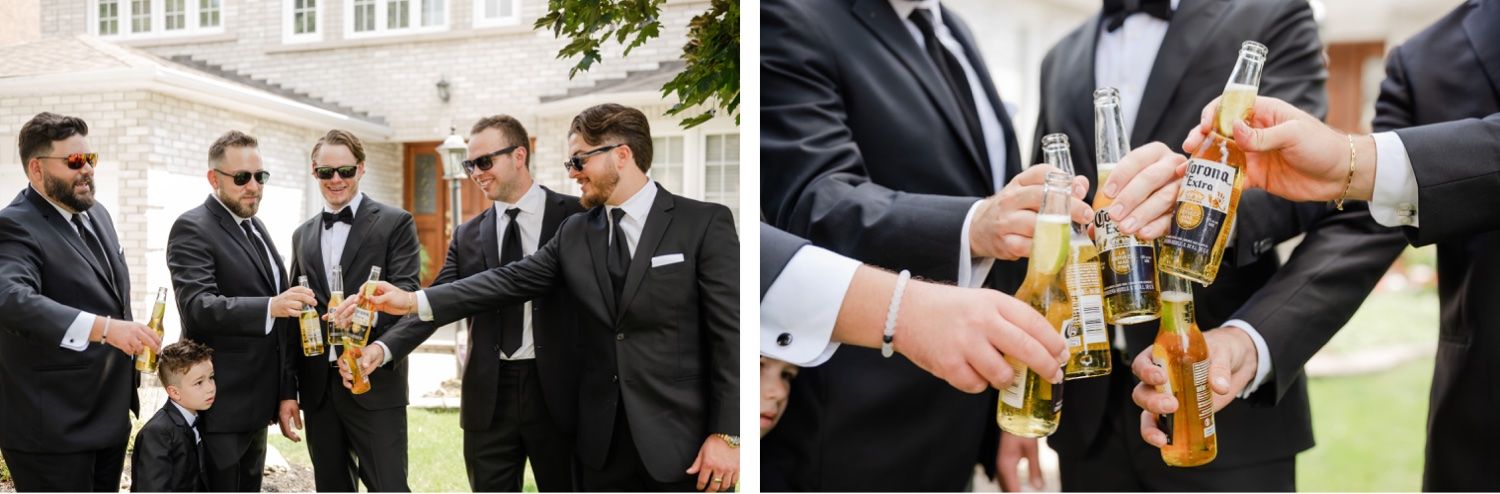 Groomsmen toasting with beer bottles outside white brick building.