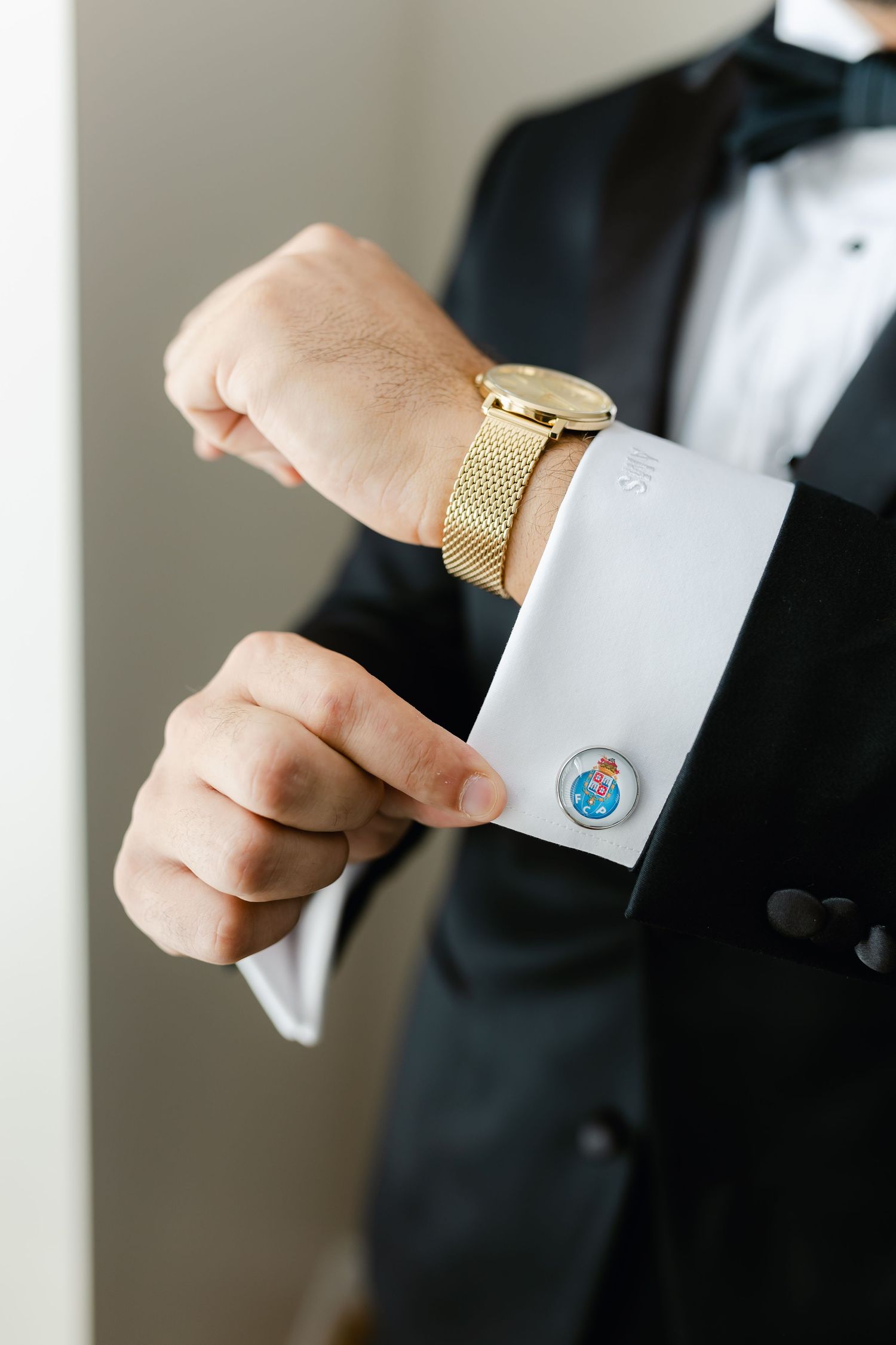 Close up of groom's wrist showing gold watch and blue gemstone cufflink.