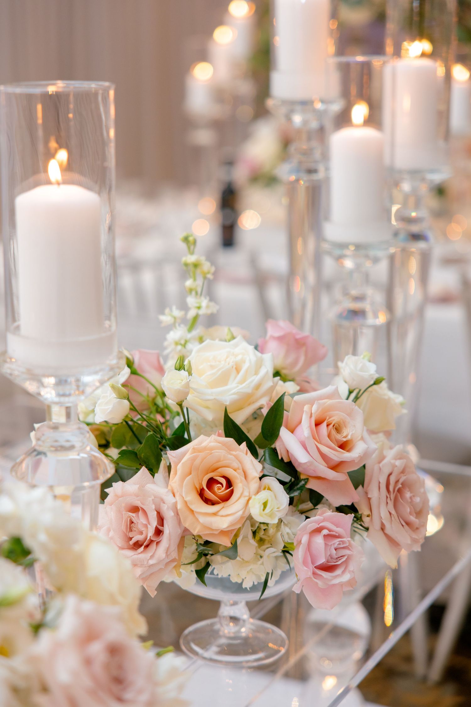 Romantic floral arrangement with pink and white roses alongside glowing pillar candles.