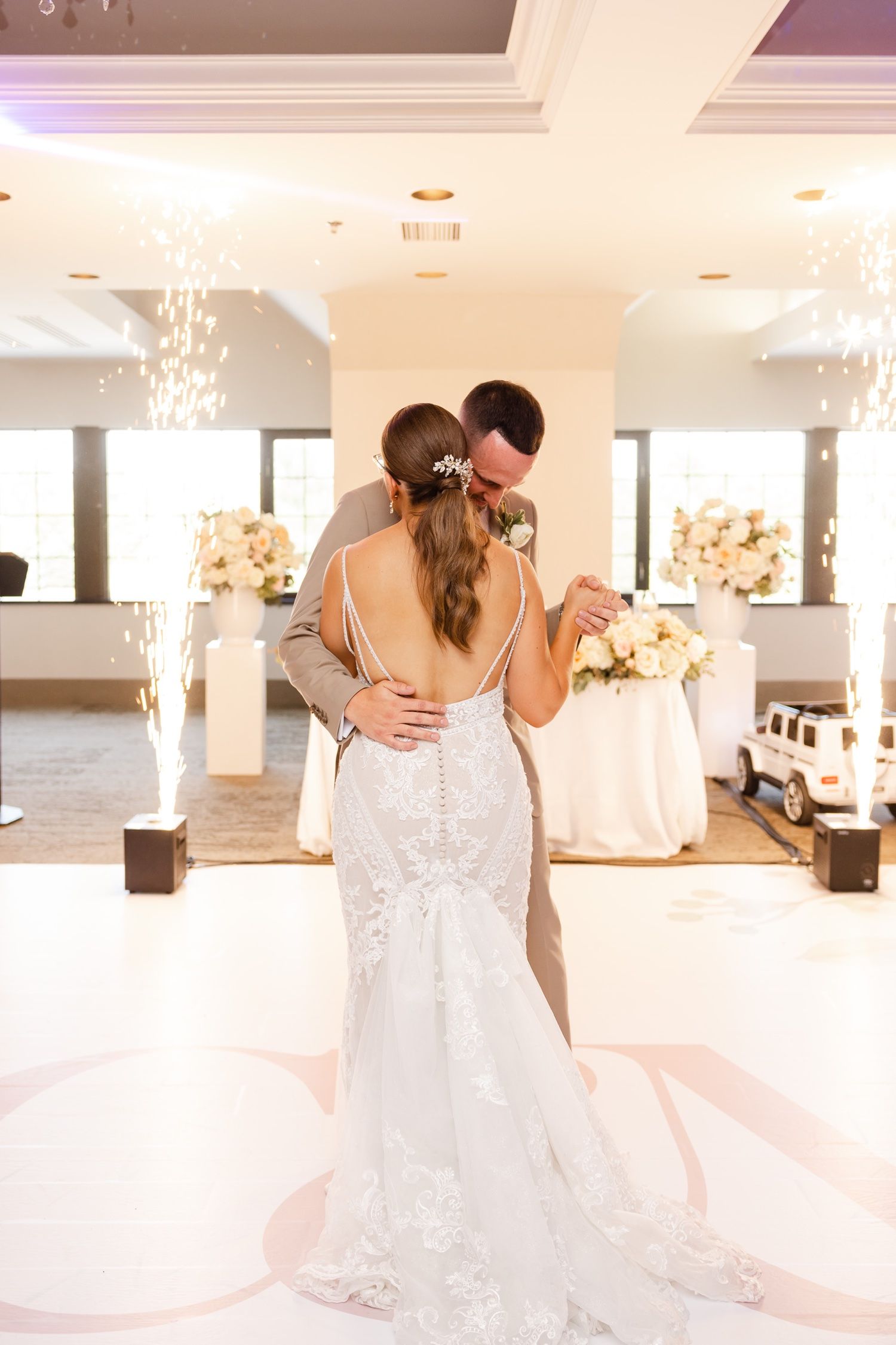 Couple shares their first dance at an elegant wedding reception with sparkling lights and floral decorations.