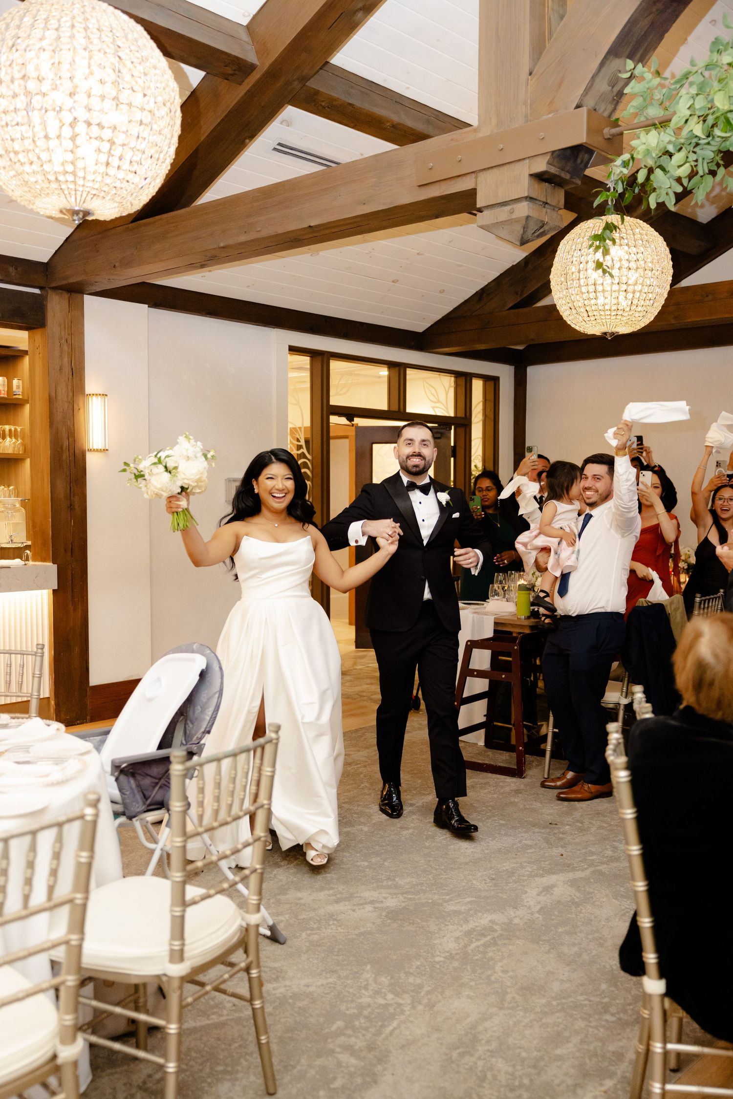 A celebratory entrance at a wedding reception with exposed wooden beams and crystal globe lights.
