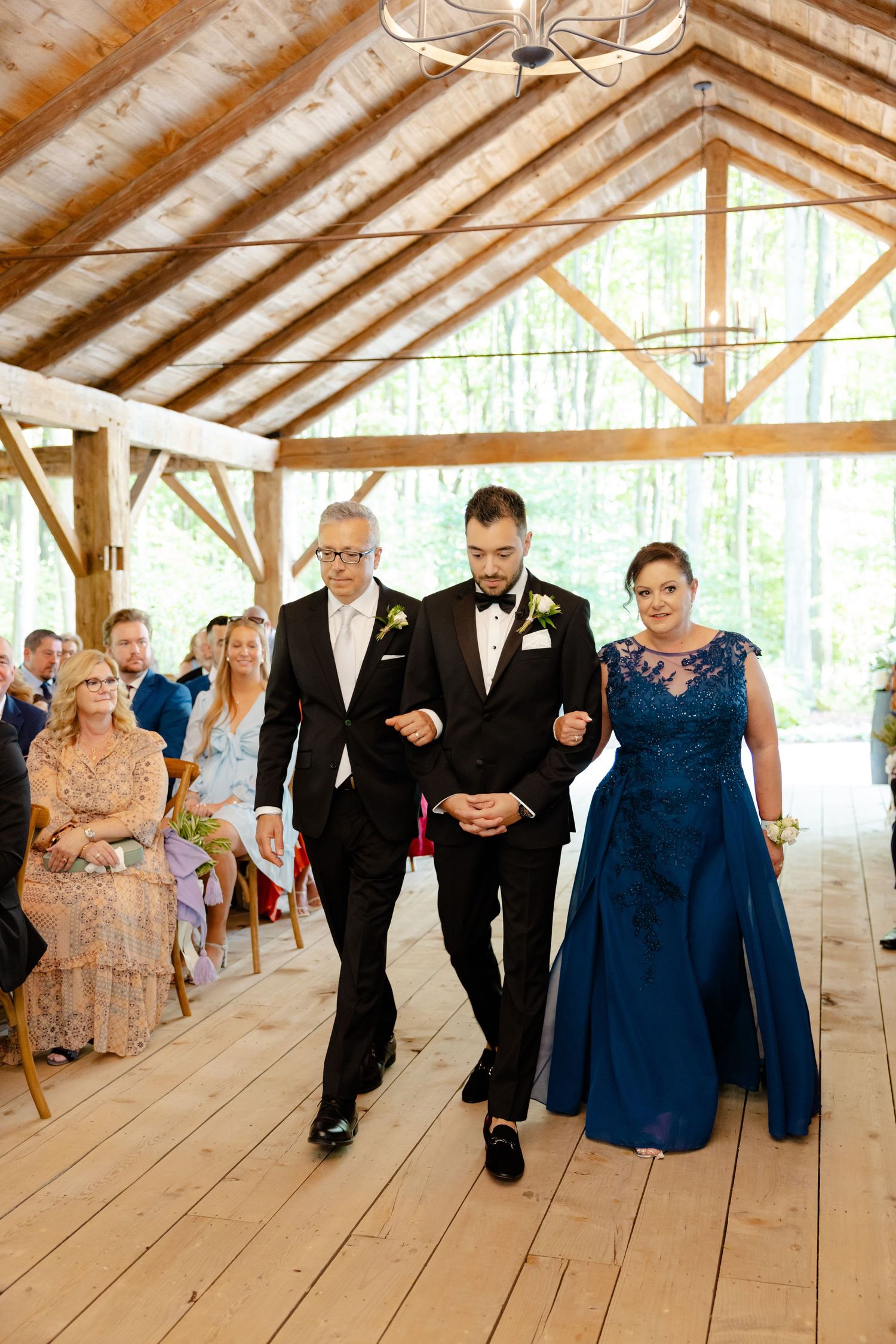 Wedding processional inside a wooden pavilion with exposed beams and natural lighting.