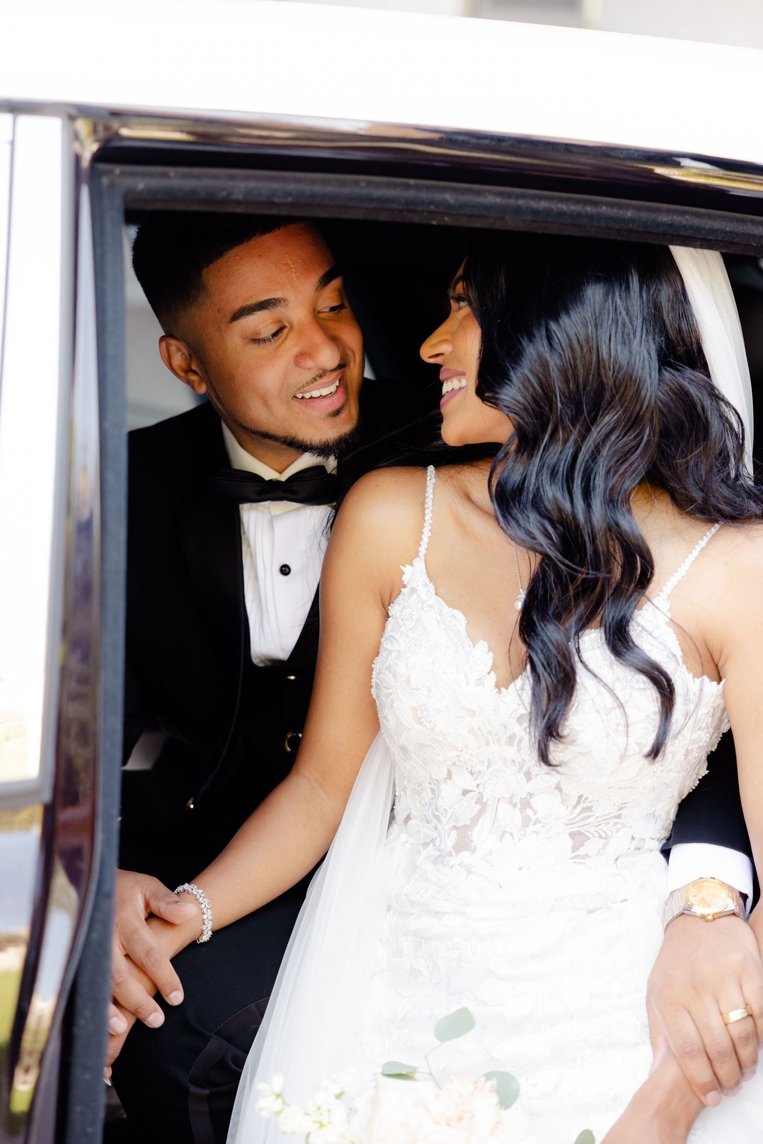 Elegant newlyweds share a tender moment in the backseat of their wedding car.