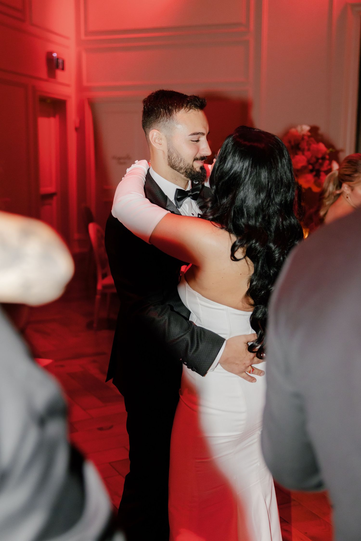 A couple dances under dramatic red lighting at their wedding reception.