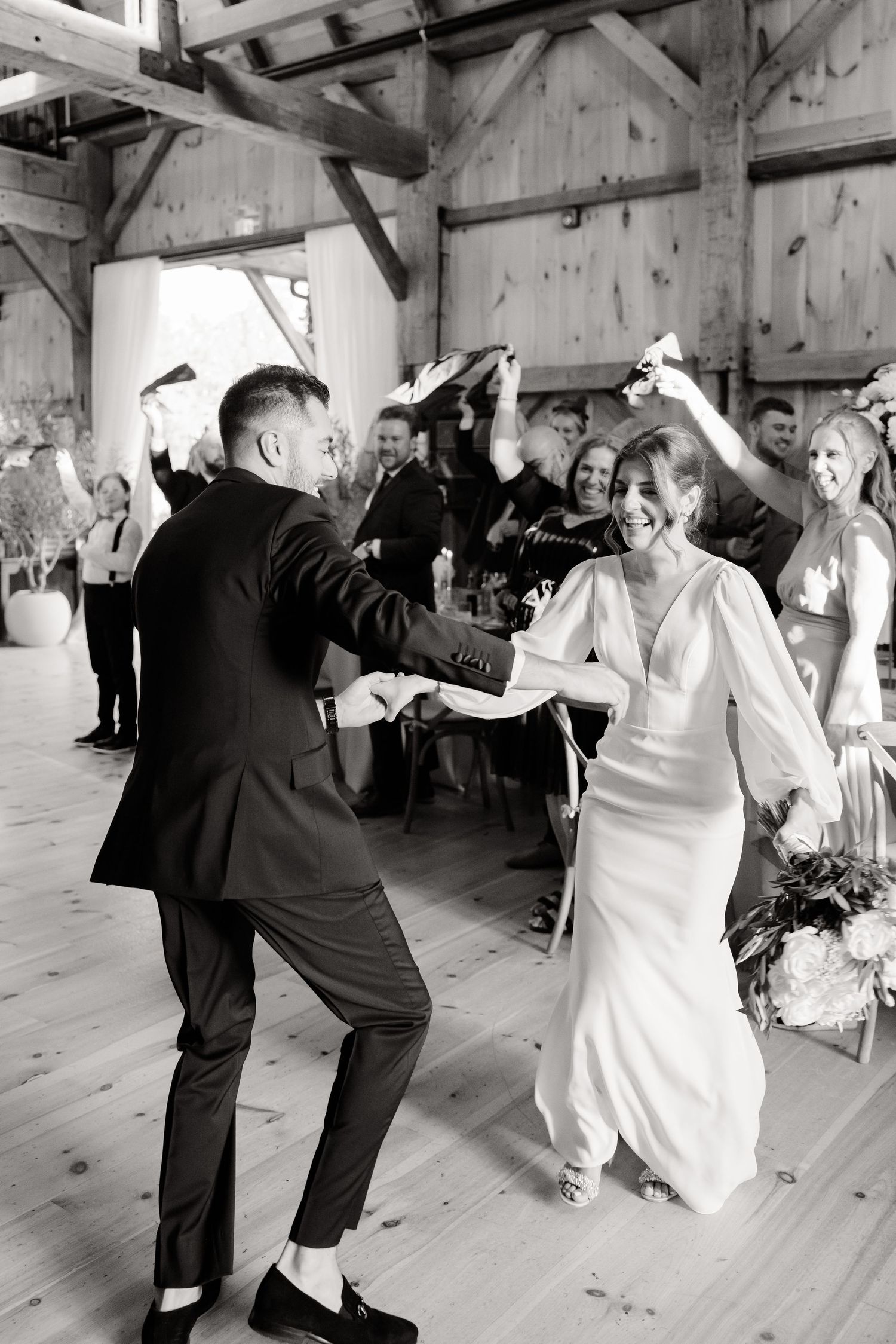 A celebration on a rustic wooden dance floor with guests dancing energetically at a wedding reception.