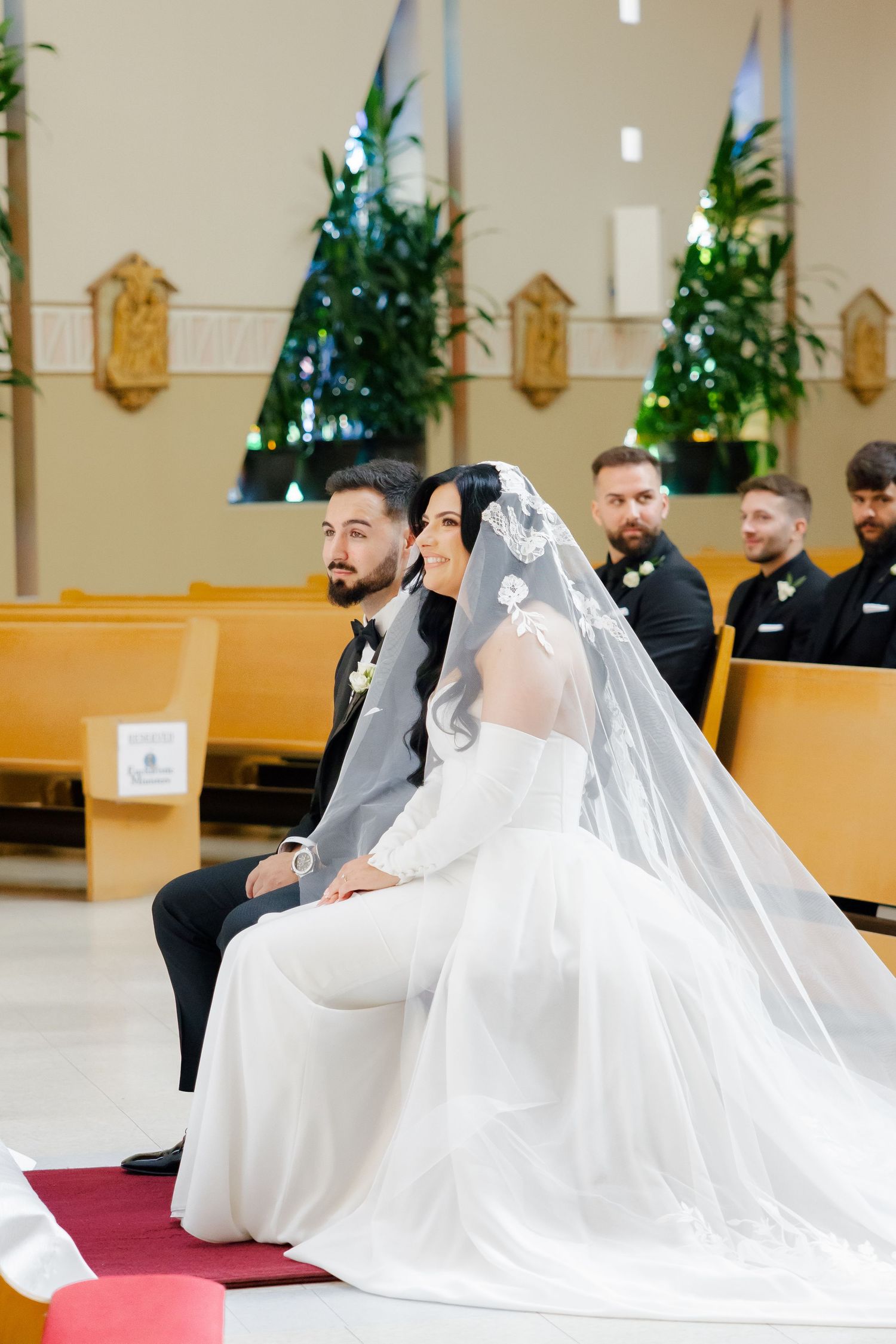 Couple seated during their Catholic church wedding ceremony.