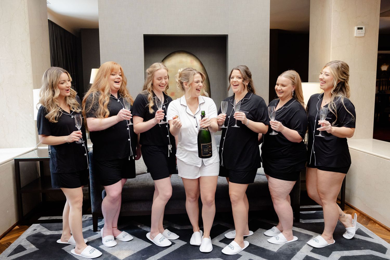 Group of women in black and white outfits posing together and laughing during a celebration.