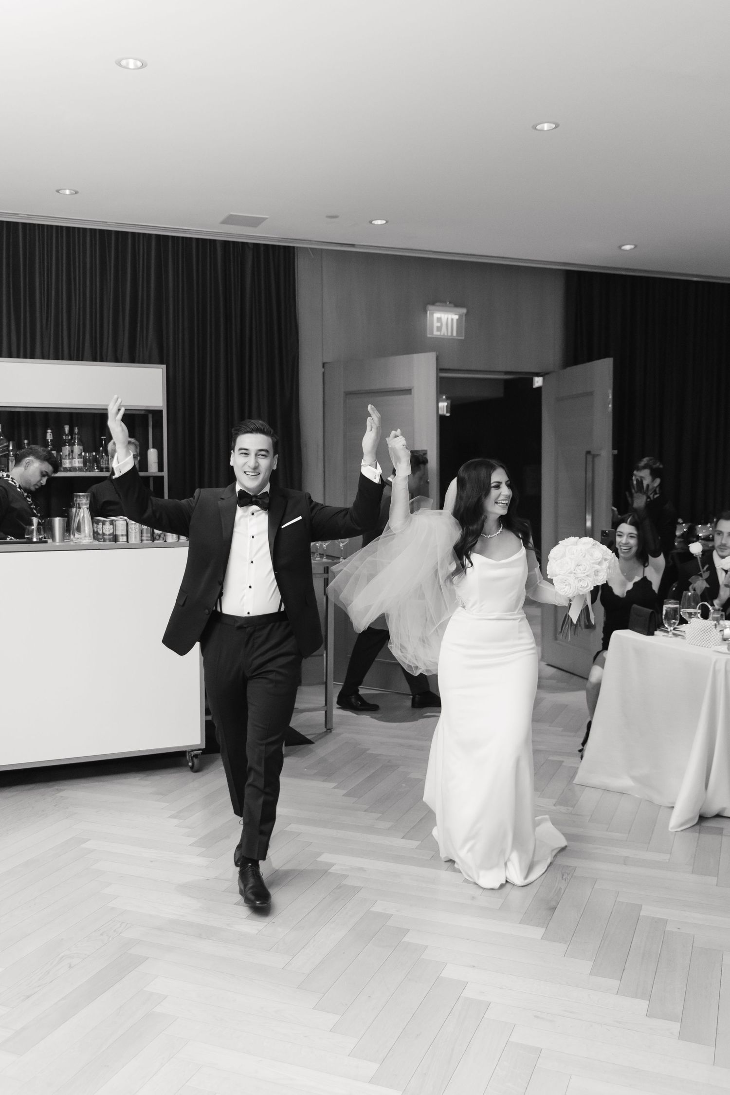 Black and white photo of elegant wedding reception venue with parquet flooring and curtained walls.