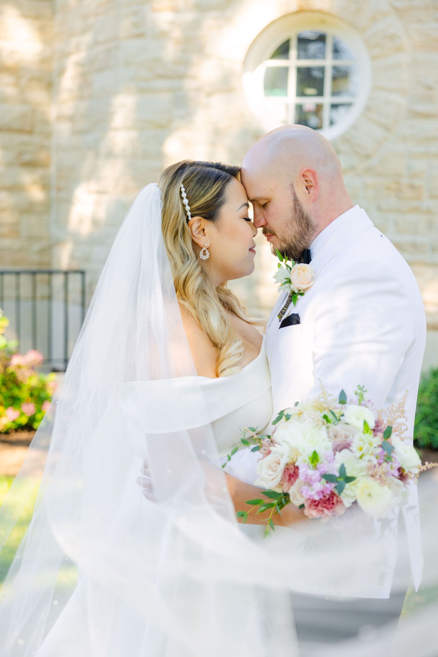 An intimate wedding portrait with flowing veil and delicate floral bouquet.
