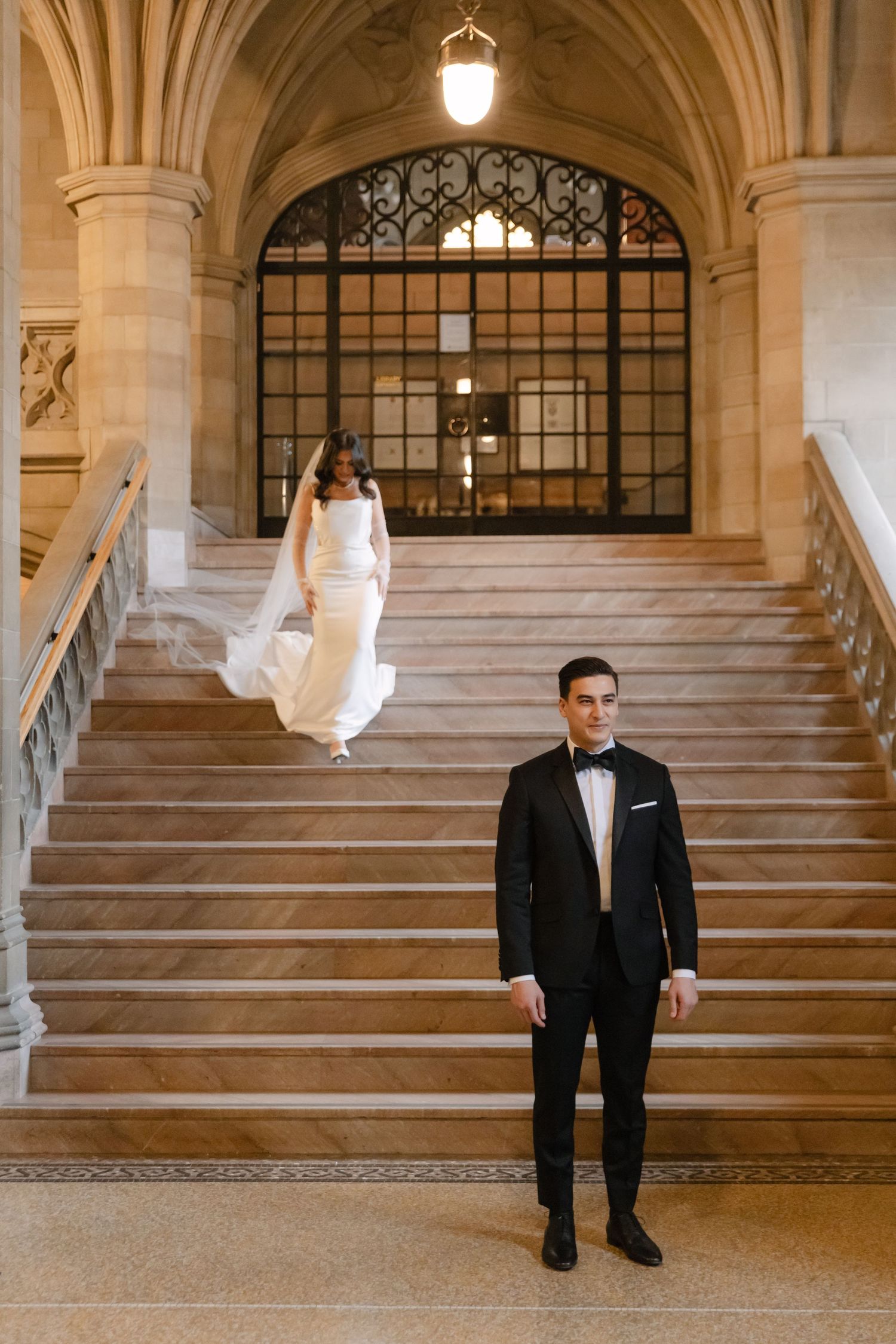 Wedding photo featuring formal attire against dramatic architectural backdrop with stone stairs.