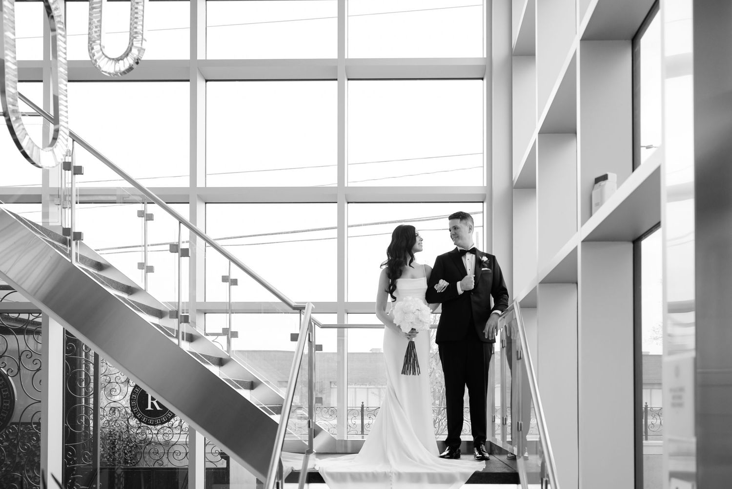 Black and white wedding portrait on contemporary staircase with dramatic lighting.