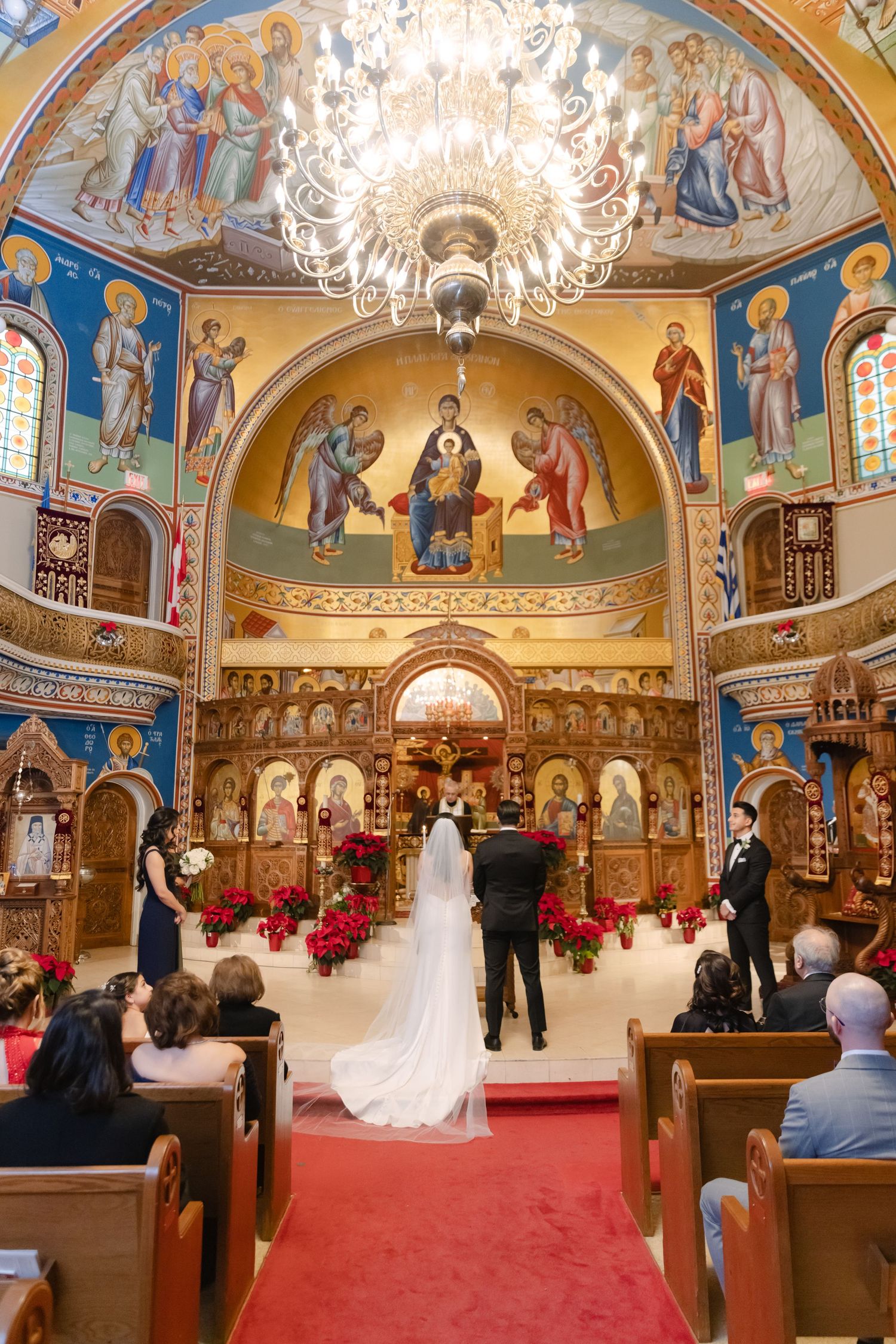 Orthodox church interior with stunning frescoes and chandelier during wedding ceremony.