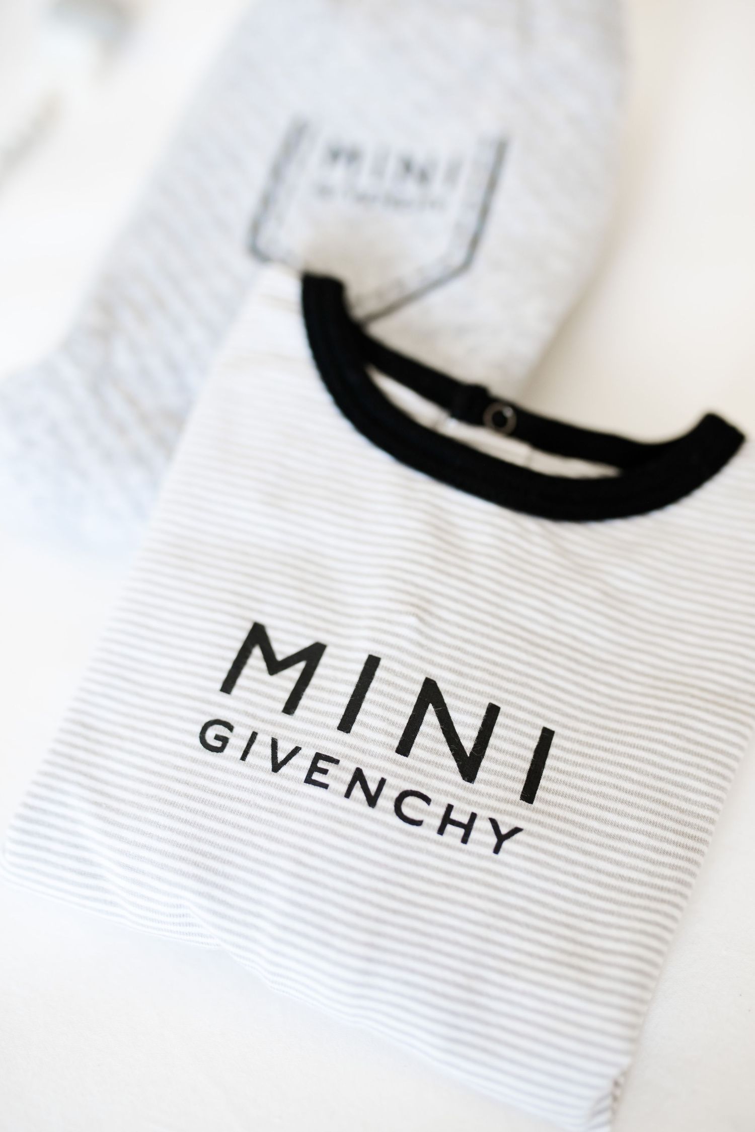 White striped Mini Givenchy baby clothing with black text and neckline detail.
