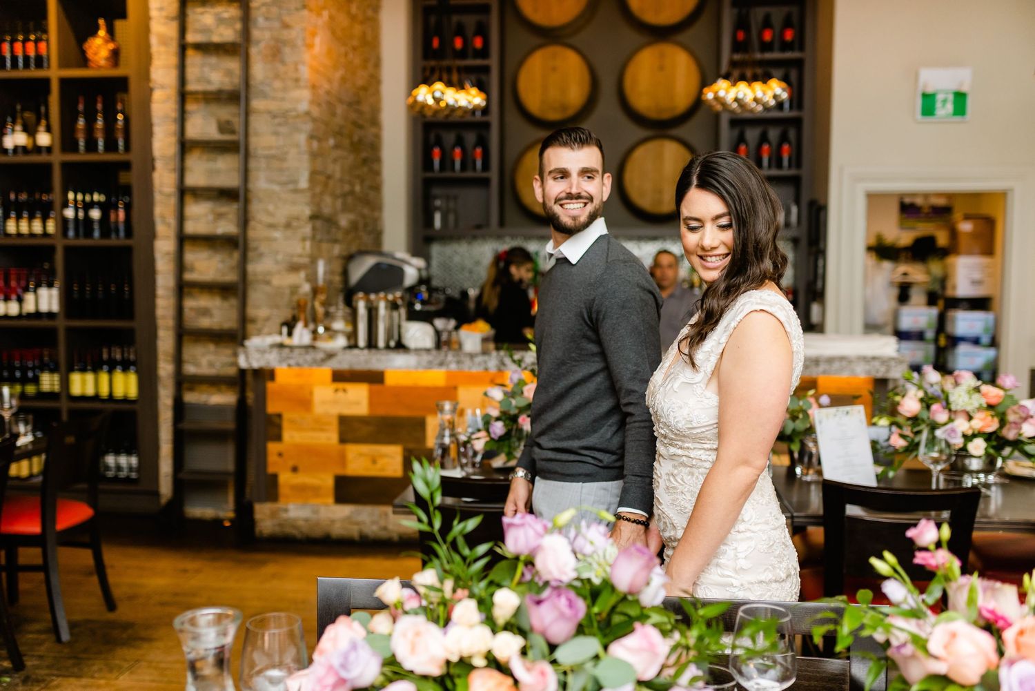 Romantic portrait in wine cellar setting with floral arrangements and barrel decor.
