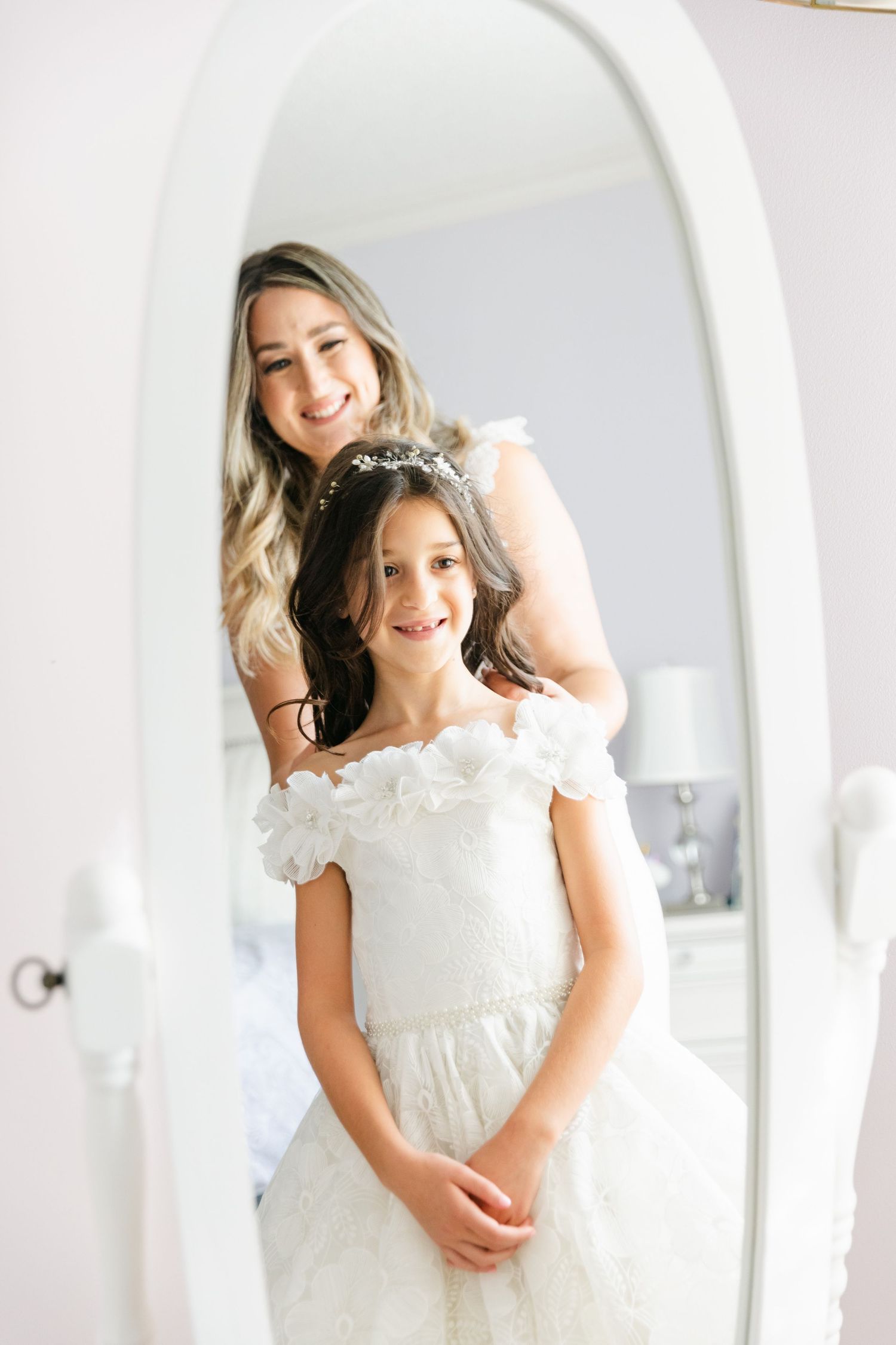 Elegant mirror reflection shows white dress with off-shoulder design.