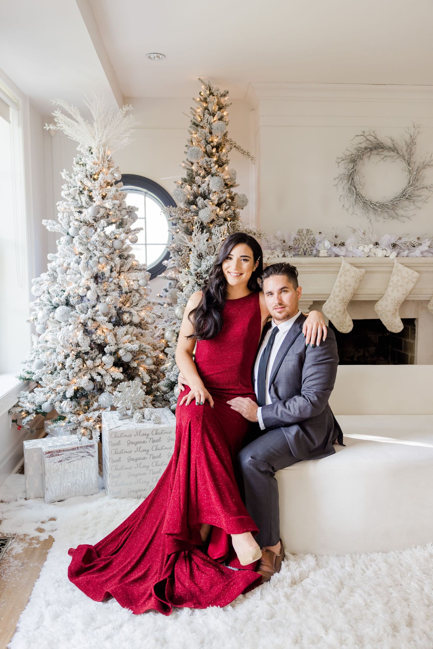 Glamorous red gown and grey suit contrast beautifully against snowy Christmas decor.