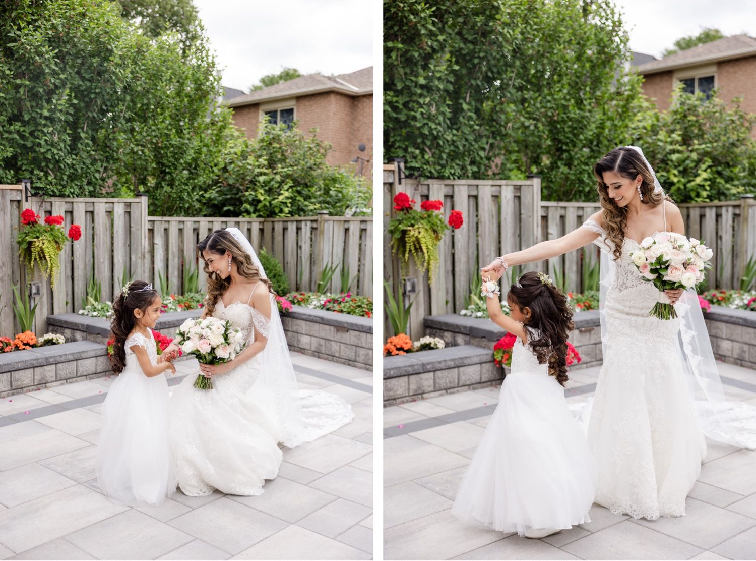 A tender moment between a bride in white and young flower girl sharing flowers in an outdoor garden setting.