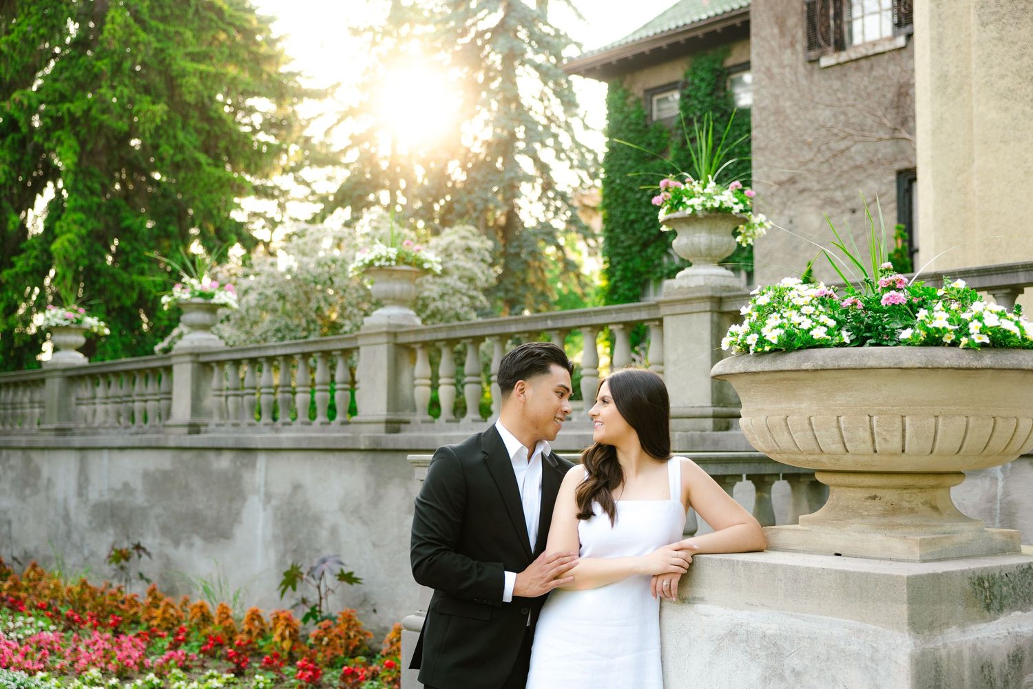A romantic moment shared beside an ornate stone fountain with blooming flowers in the background.