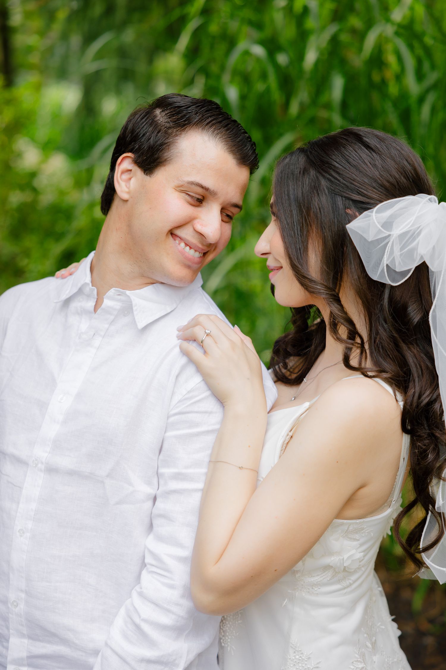 A joyful moment between a wedding couple as they share a laugh in a garden setting.