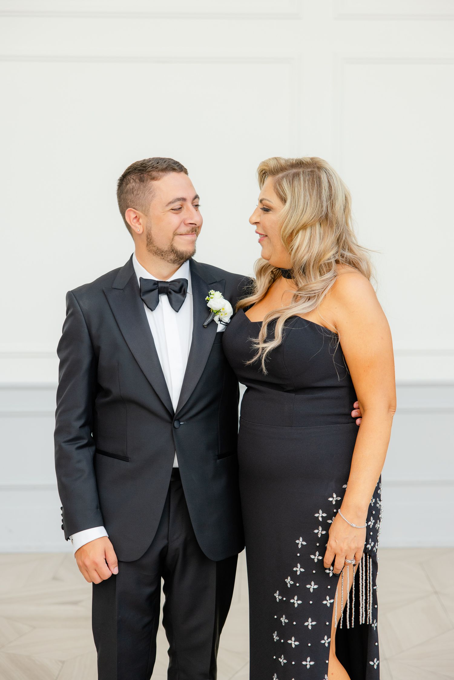 A couple shares an intimate moment while posing in formal black attire at an elegant event.