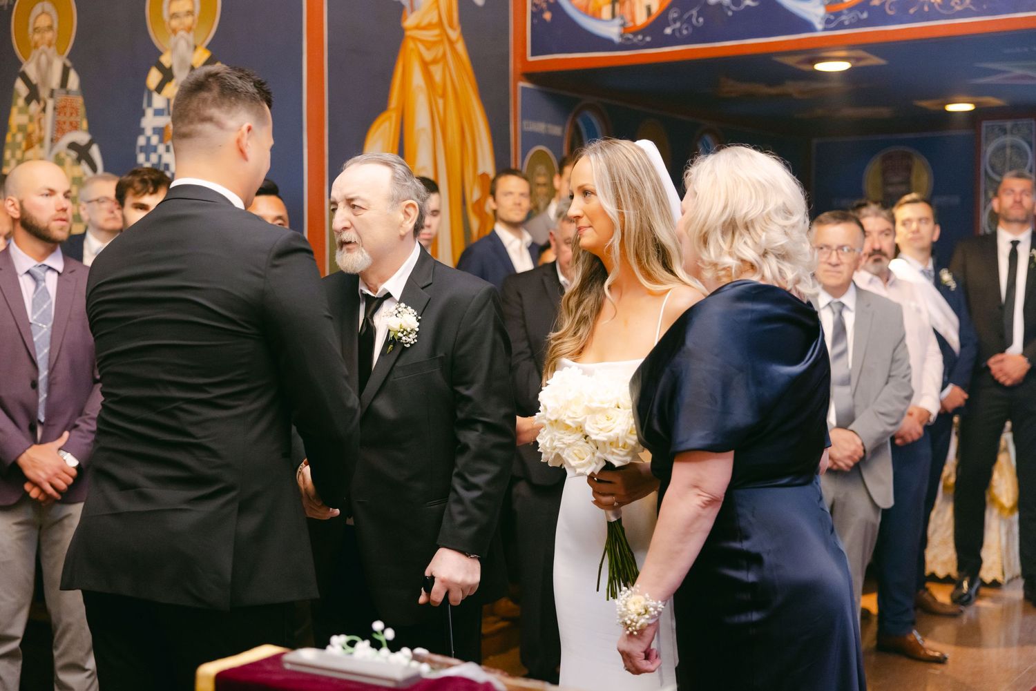 Wedding ceremony scene with guests gathered in ornate room with banners.
