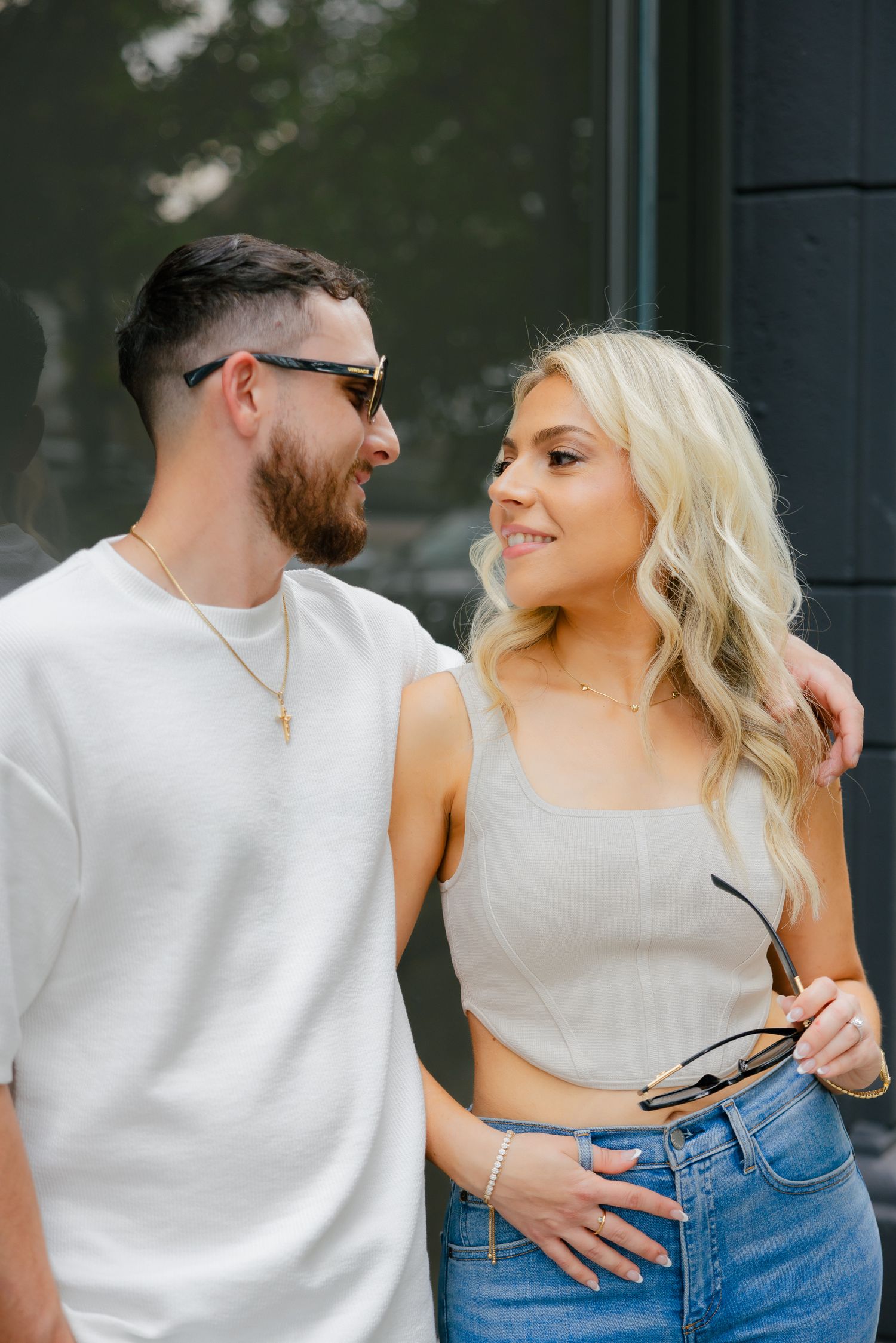 A couple in coordinated white and beige outfits sharing a tender moment outdoors.
