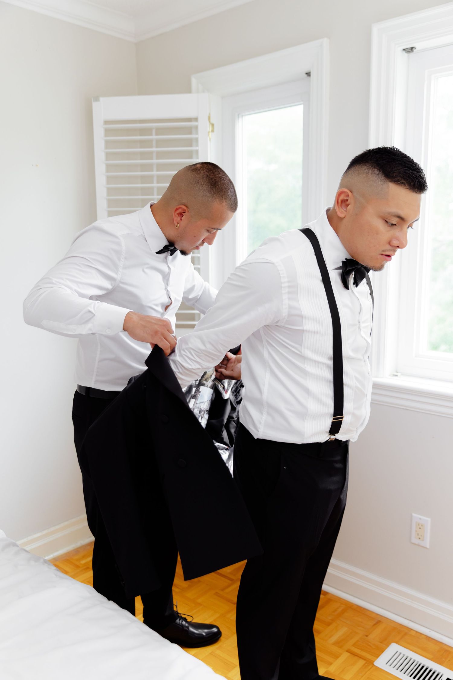 Side view of person adjusting outfit while getting ready in white room with hardwood floors and bright lighting.