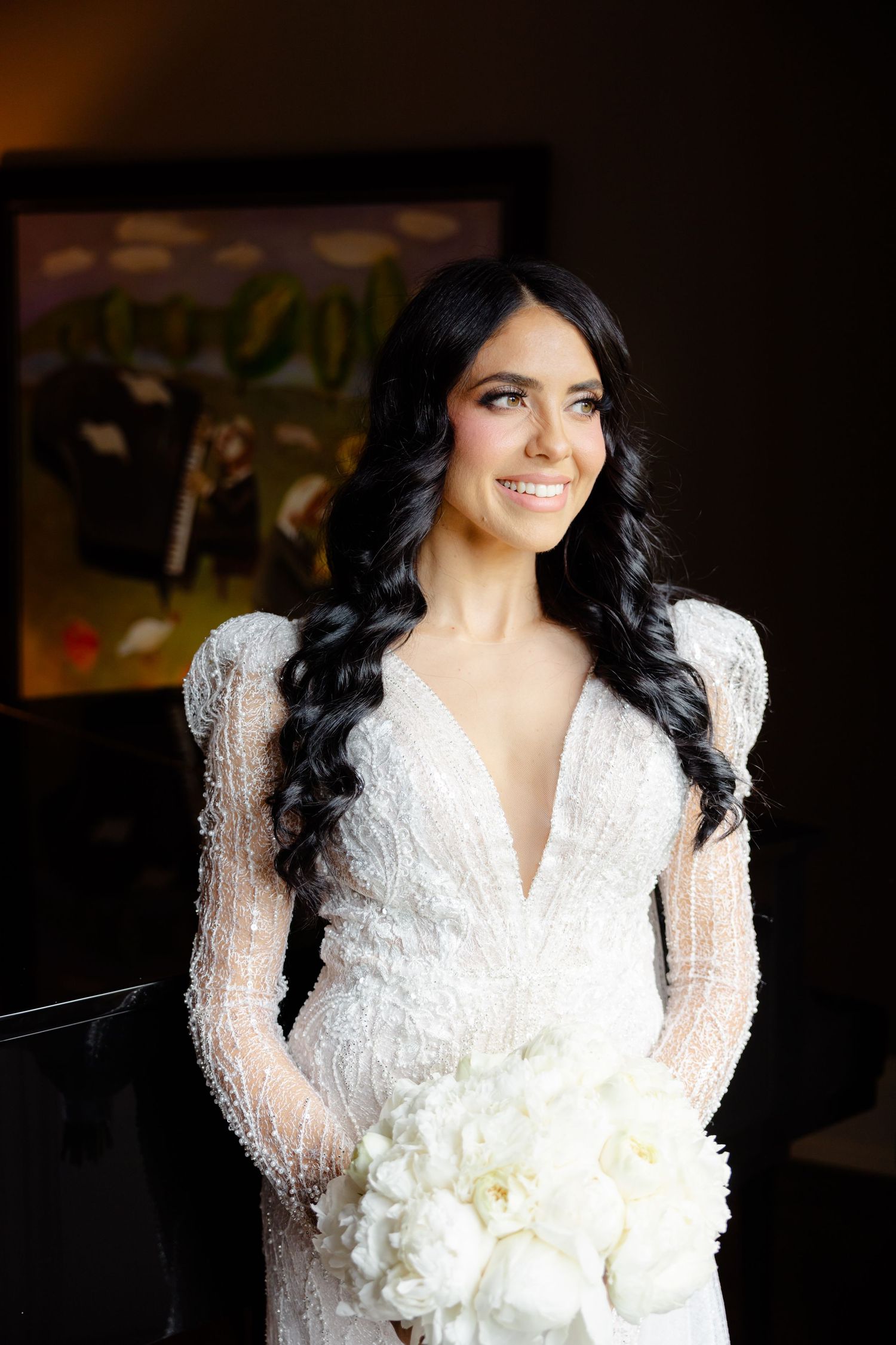 Indoor bridal portrait showcasing detailed lace wedding dress and fresh white floral bouquet.