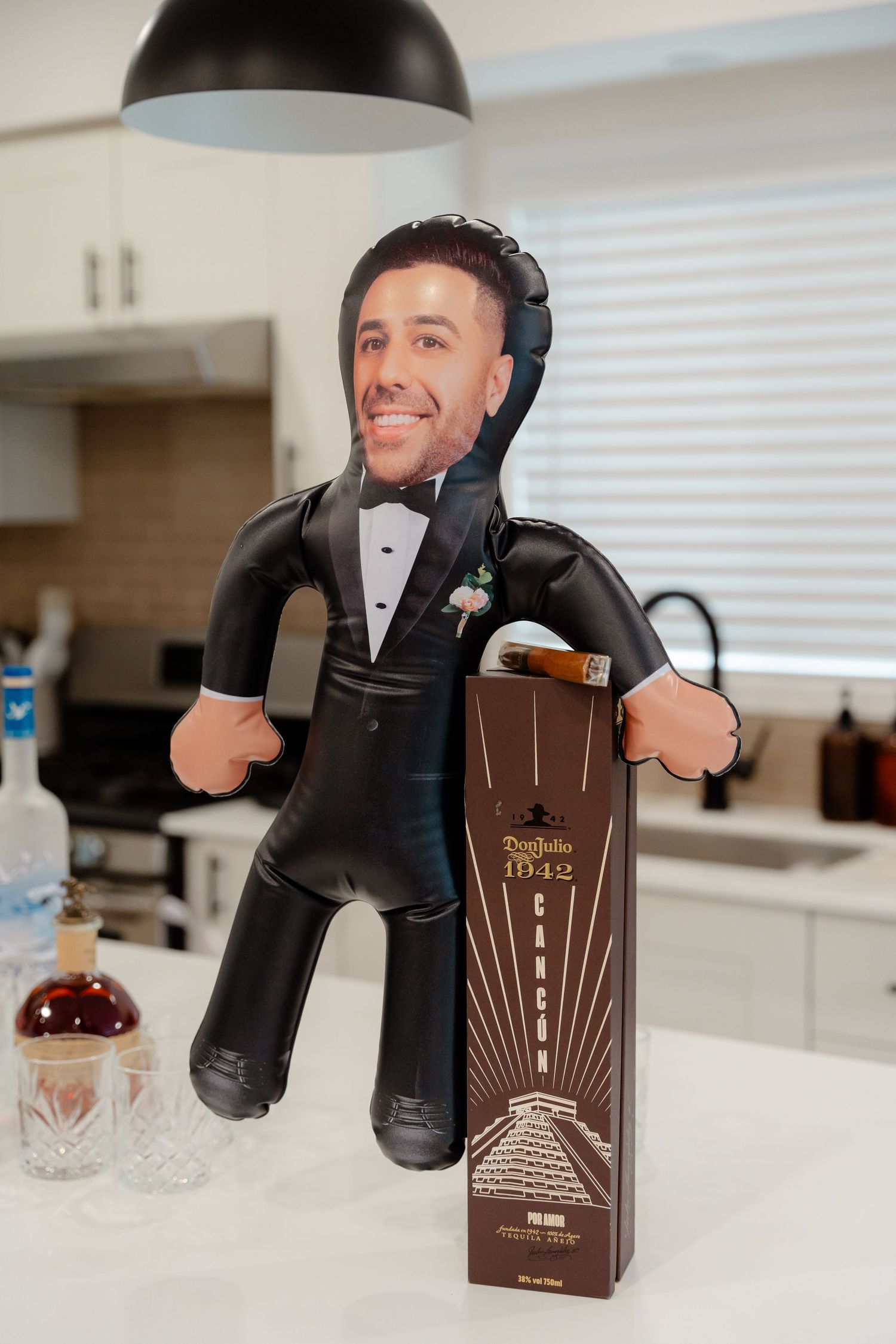 Custom inflatable doll and liquor bottle display on kitchen counter.