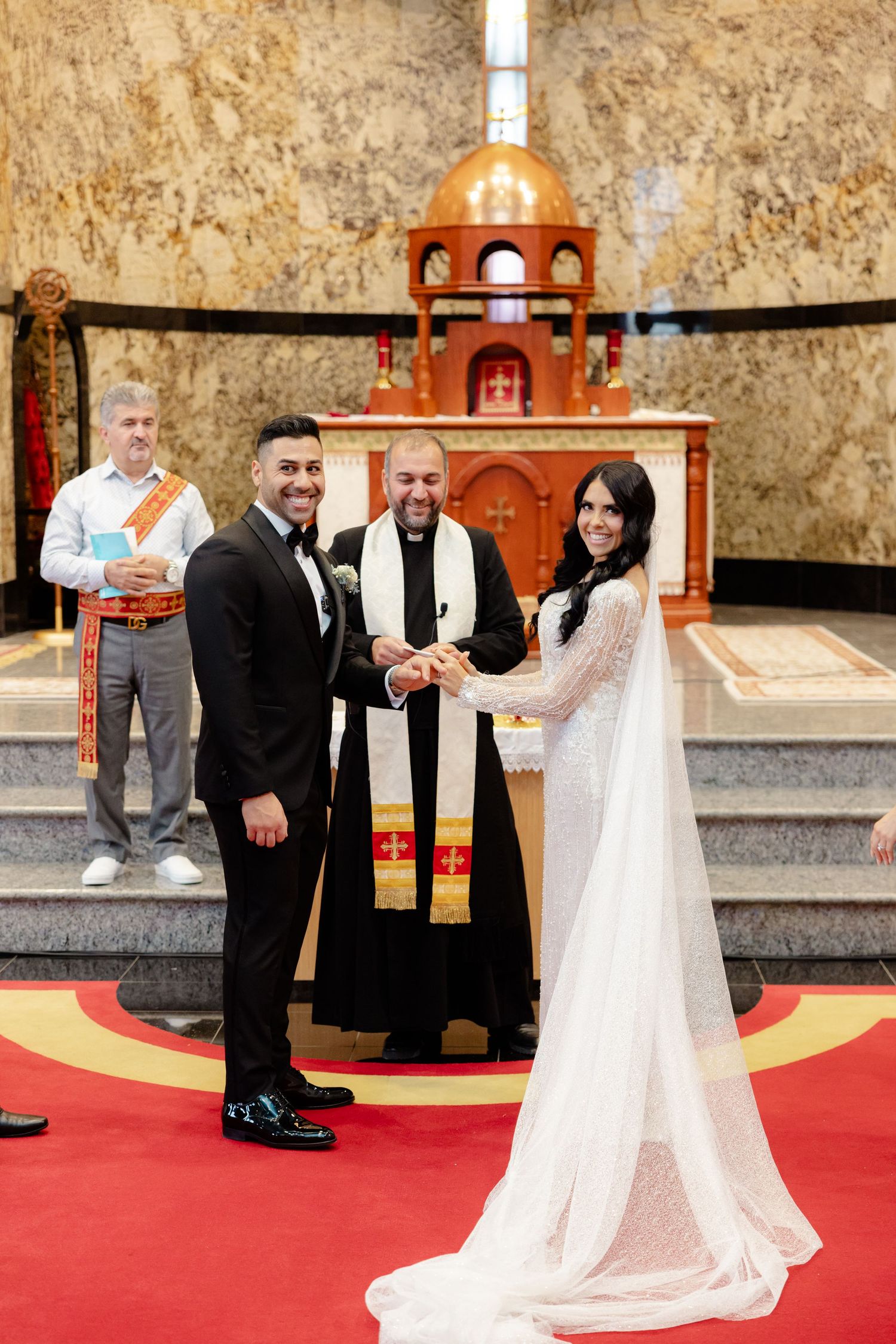 A wedding ceremony at church altar with decorative golden walls and red carpet.