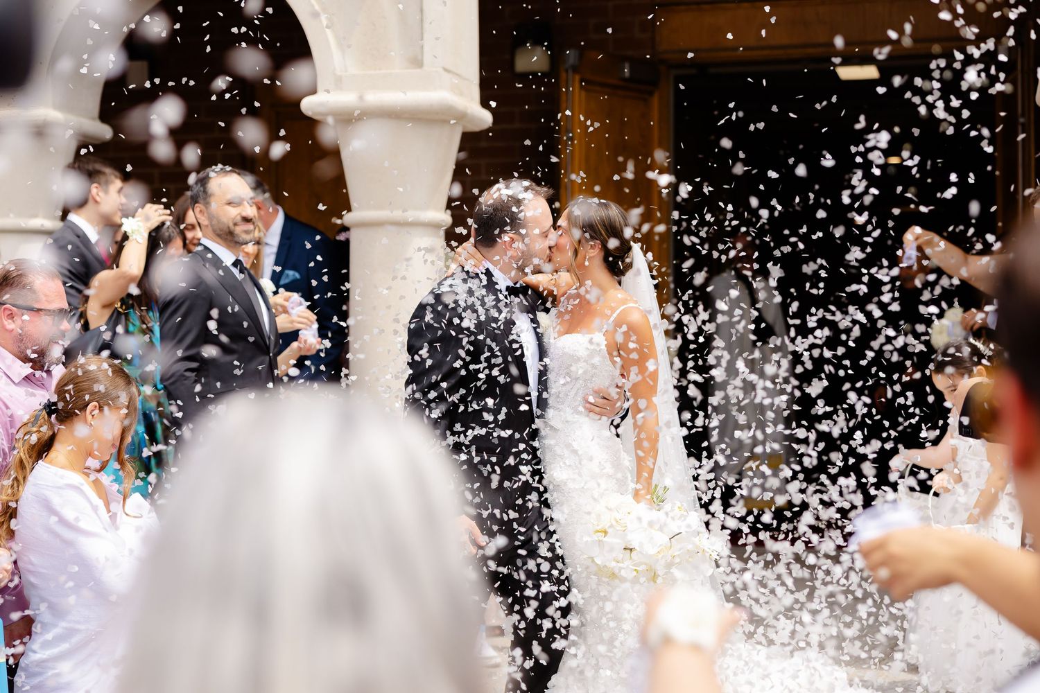 A joyful wedding celebration with snow-like confetti showering over the guests and newlyweds in an elegant venue.