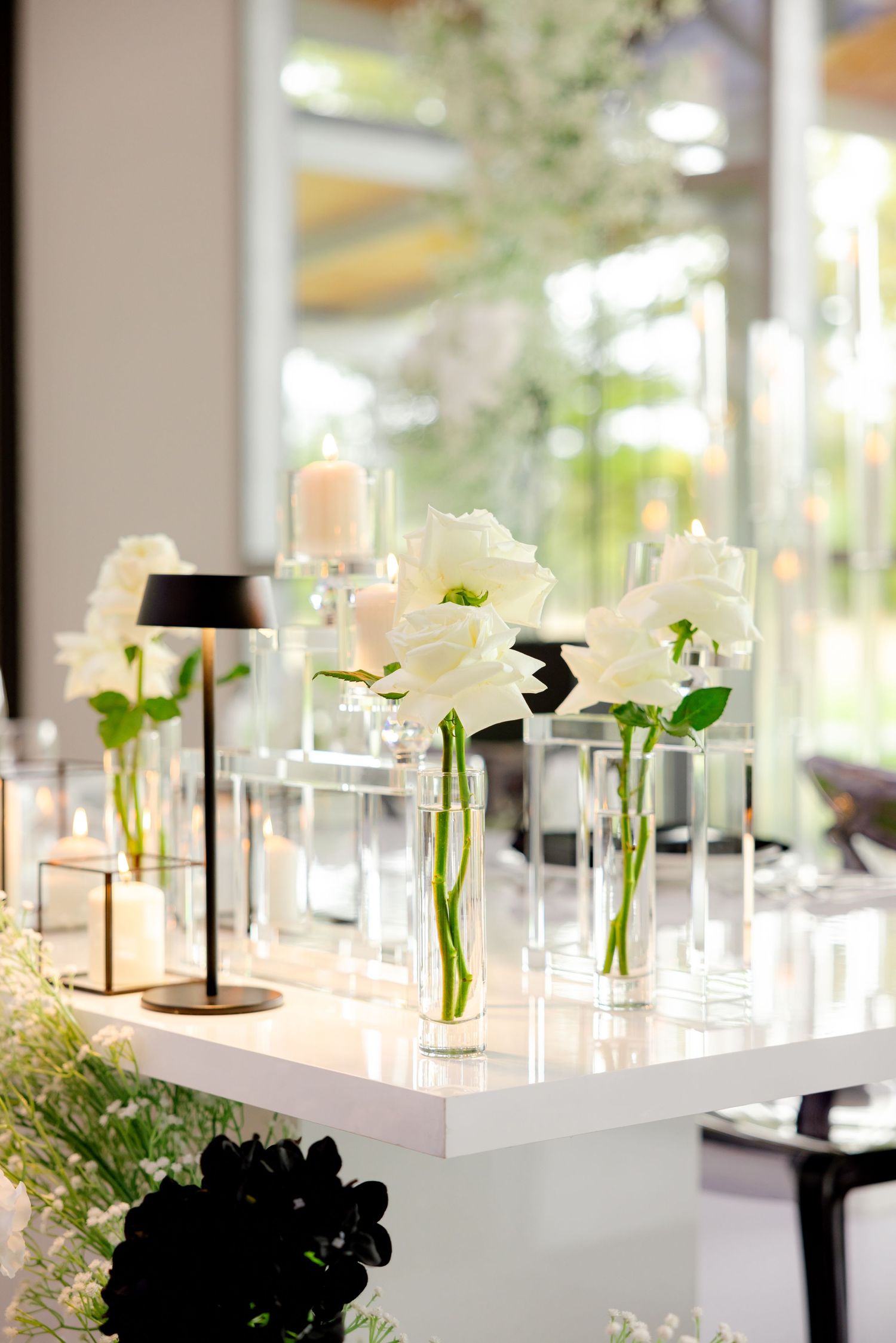 White roses in clear glass vases displayed on modern white pedestal.