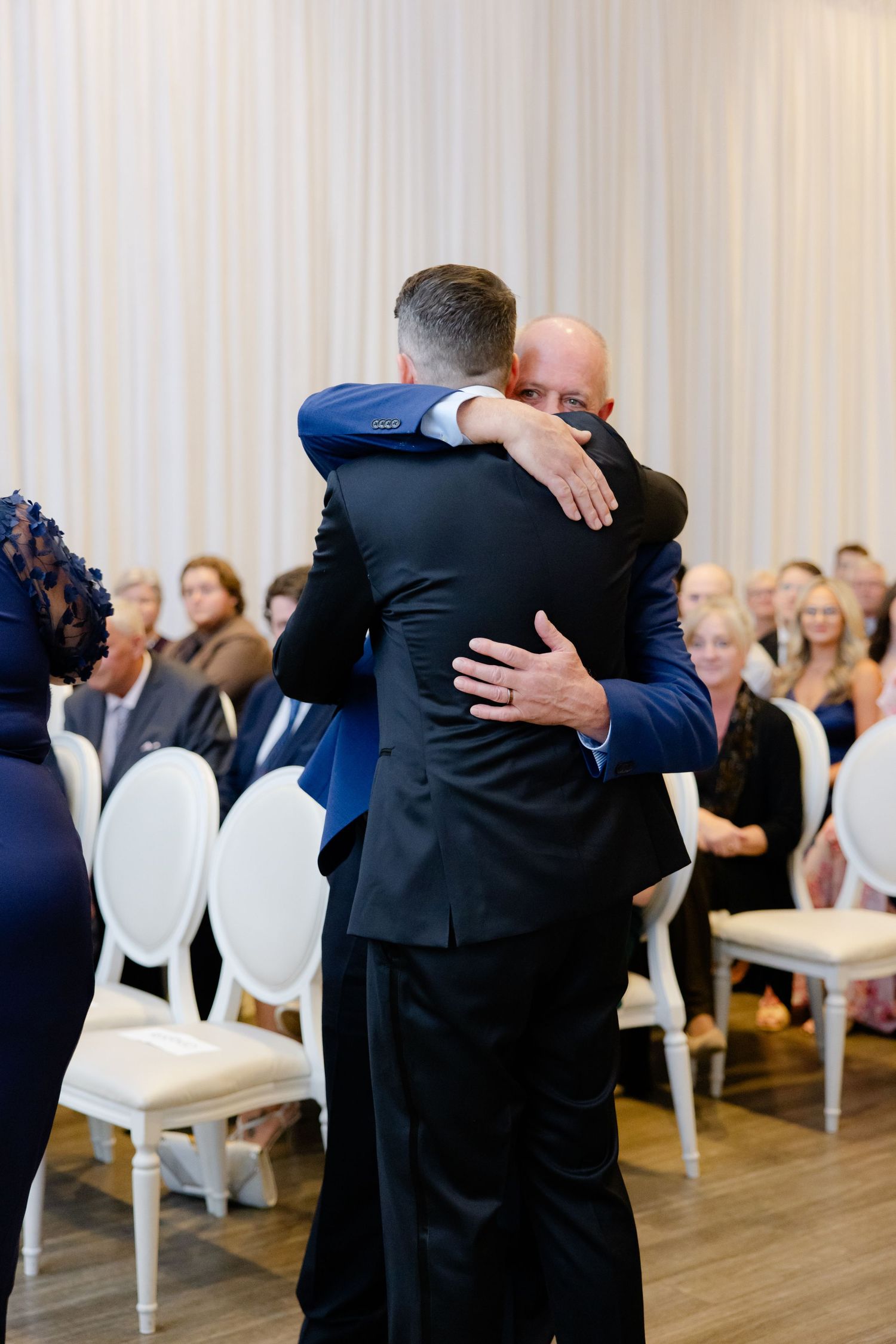 Two people share a warm embrace during an emotional moment at a wedding ceremony.